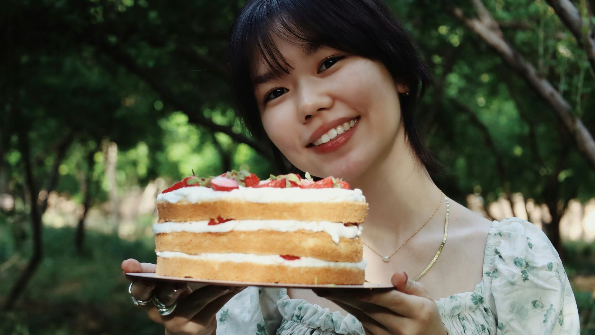 Woman smiles while holding a beautiful cake.