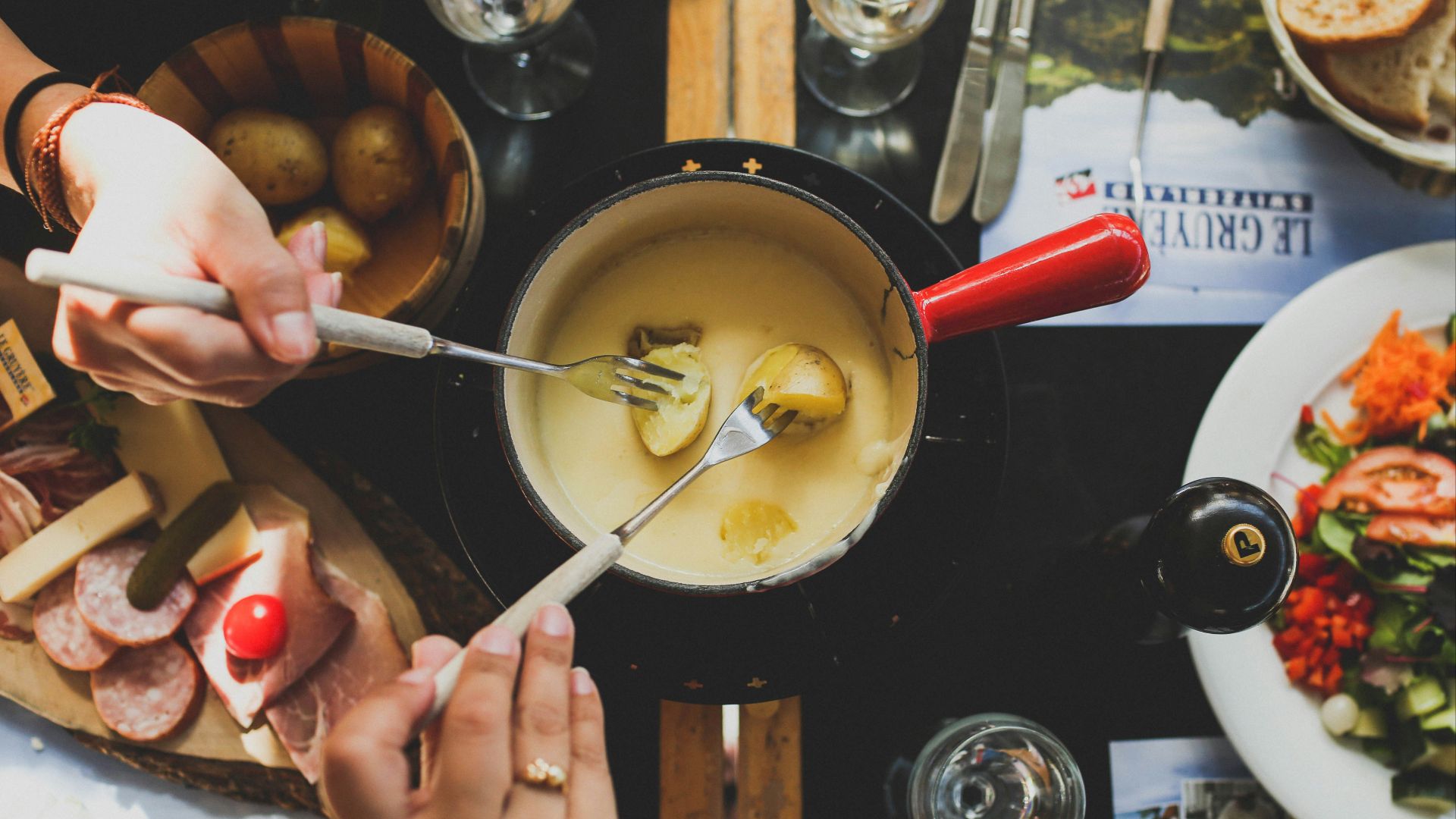 two person holding fork dipping food on sauce