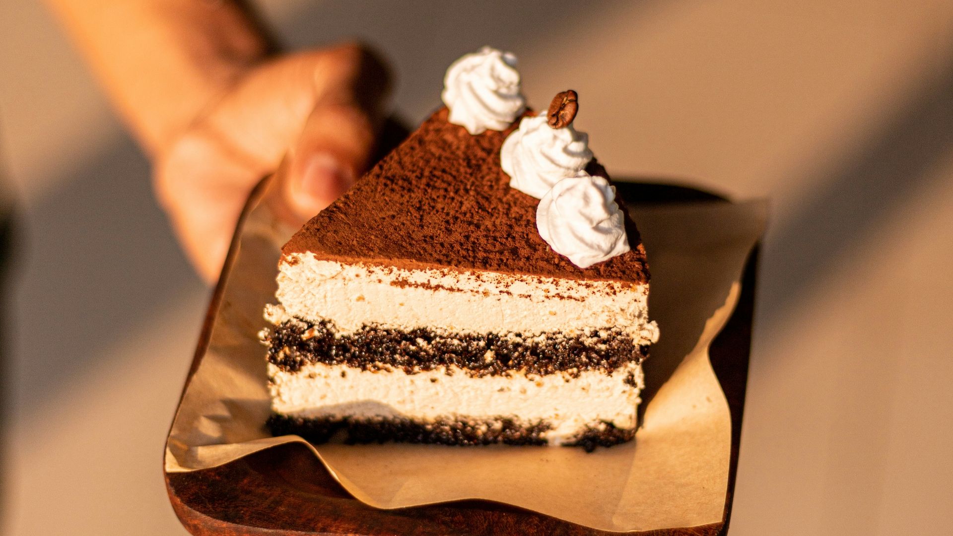 a person holding a piece of cake on a plate