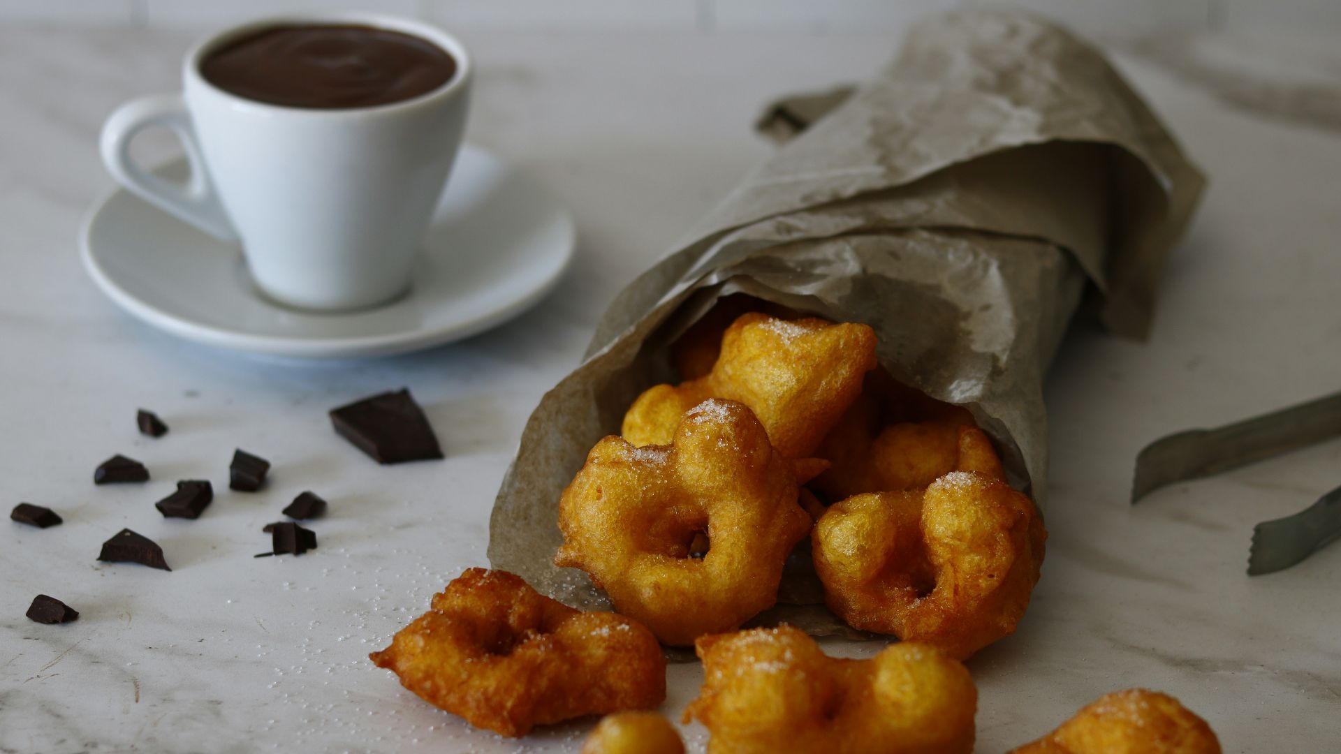 A bag of doughnuts next to a cup of coffee