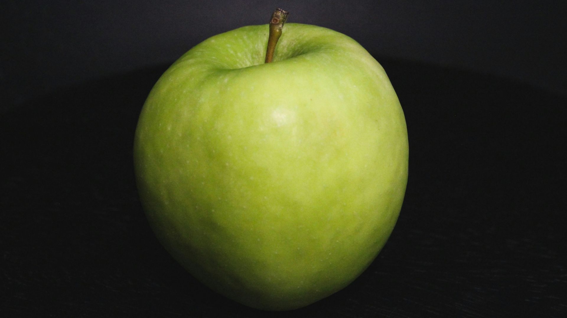 a green apple sitting on top of a table