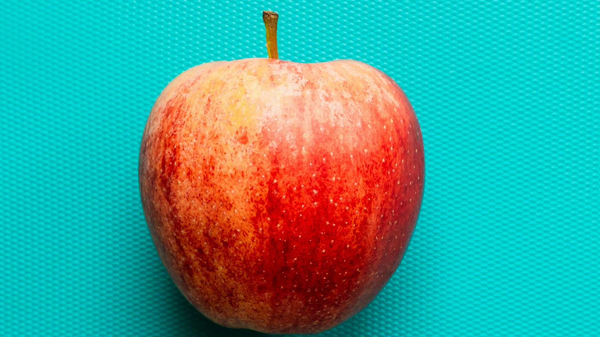 red apple fruit on blue surface