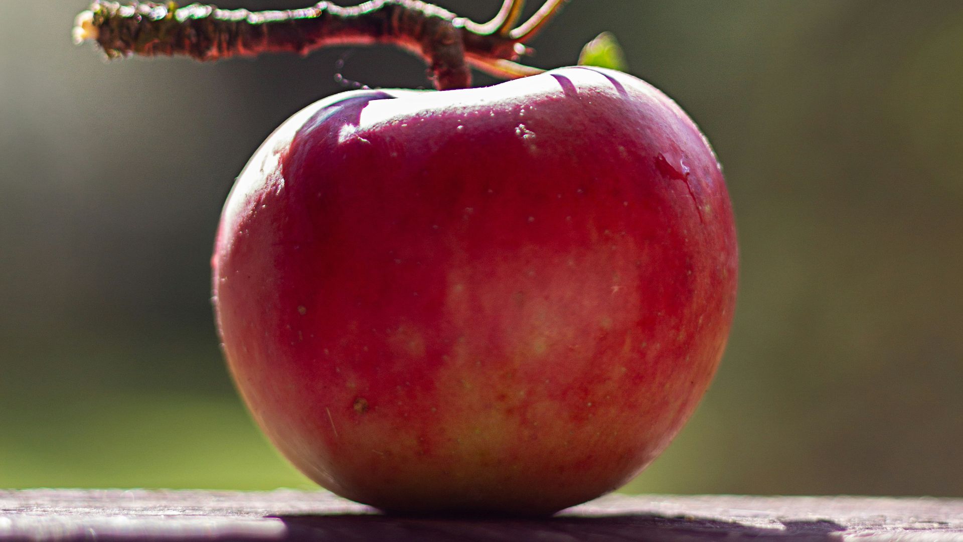 a red apple sitting on top of a wooden table
