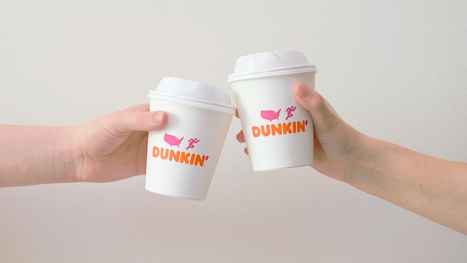 two people with white Dunkin' Donuts paper cups