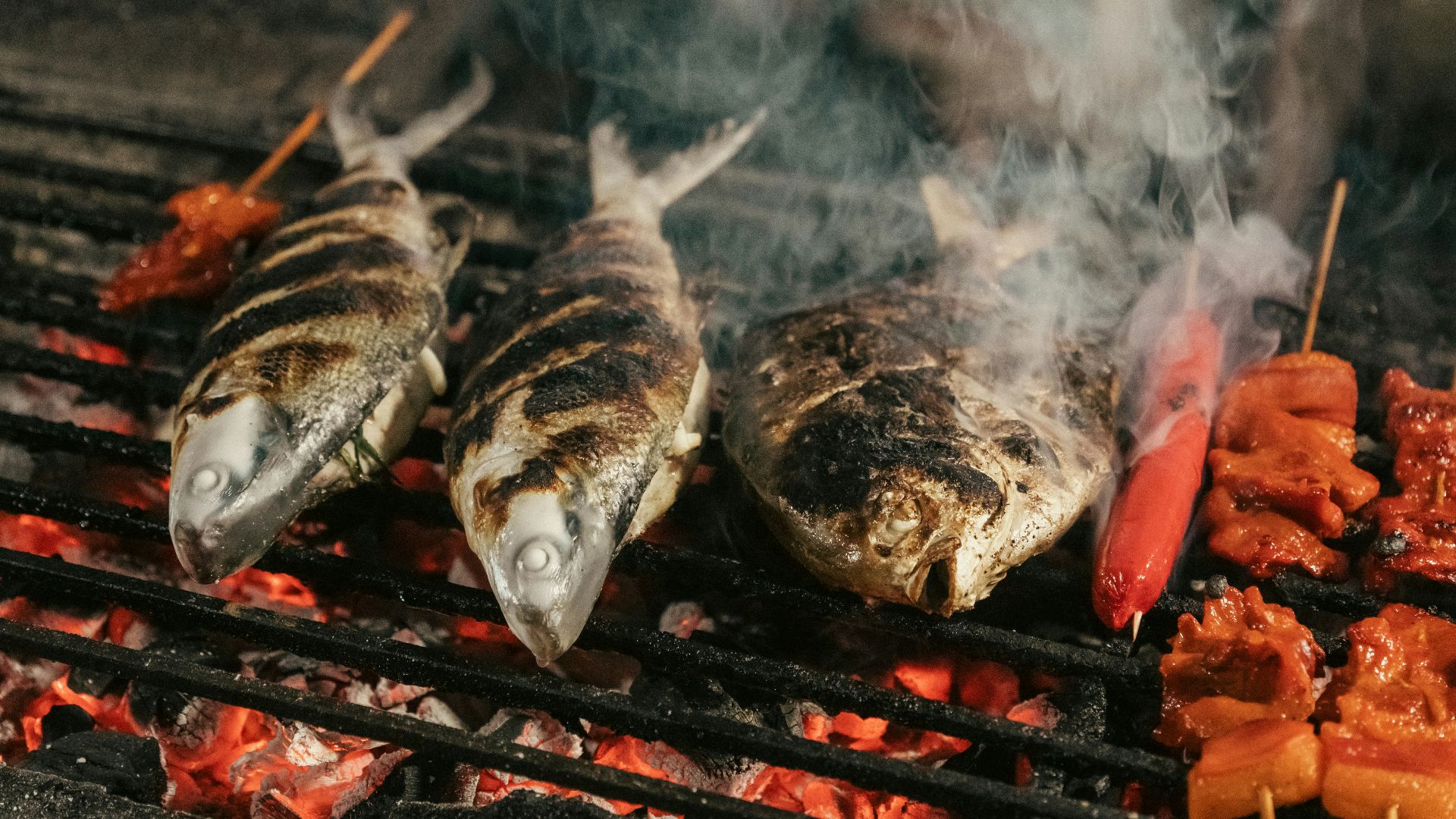 A bunch of fish are cooking on a grill