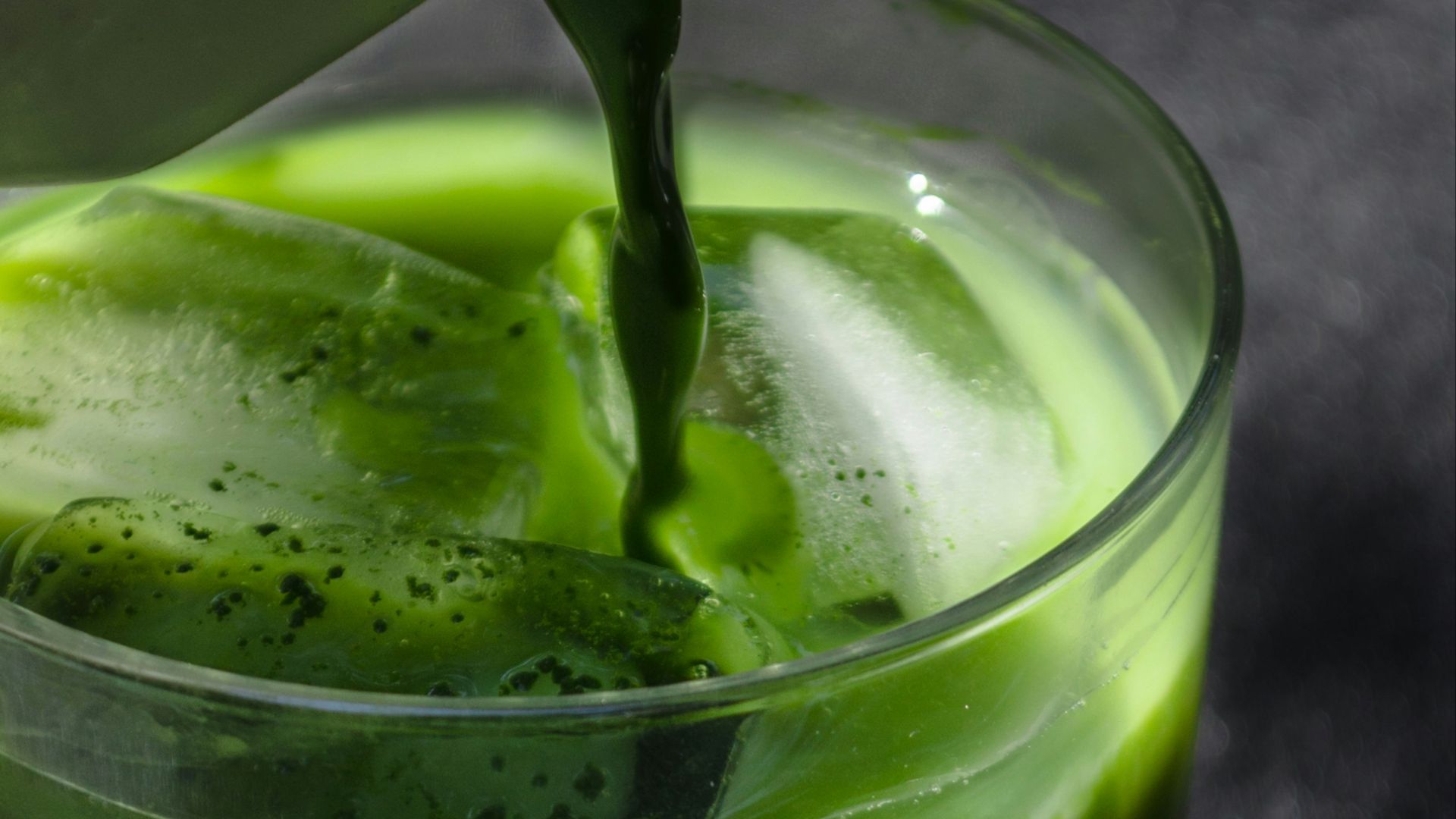 a pitcher pouring green liquid into a glass