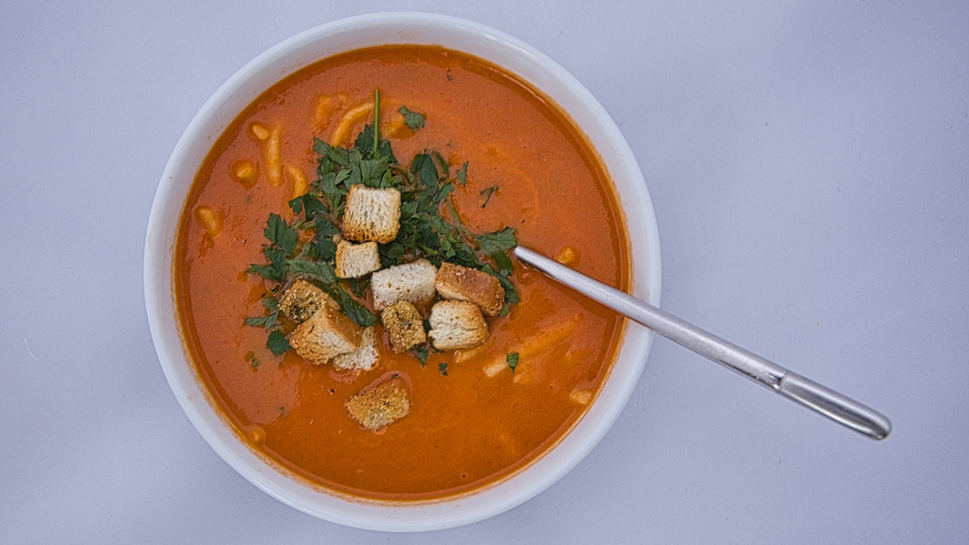 a bowl of tomato soup with croutons and spinach