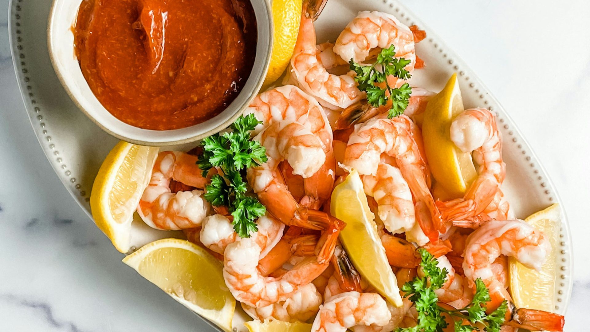 a plate of shrimp and lemons with a dipping sauce