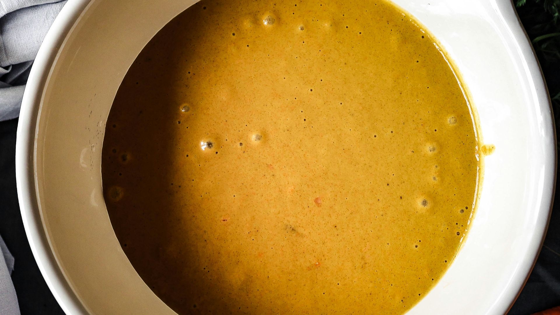 a bowl of soup with carrots and parsley