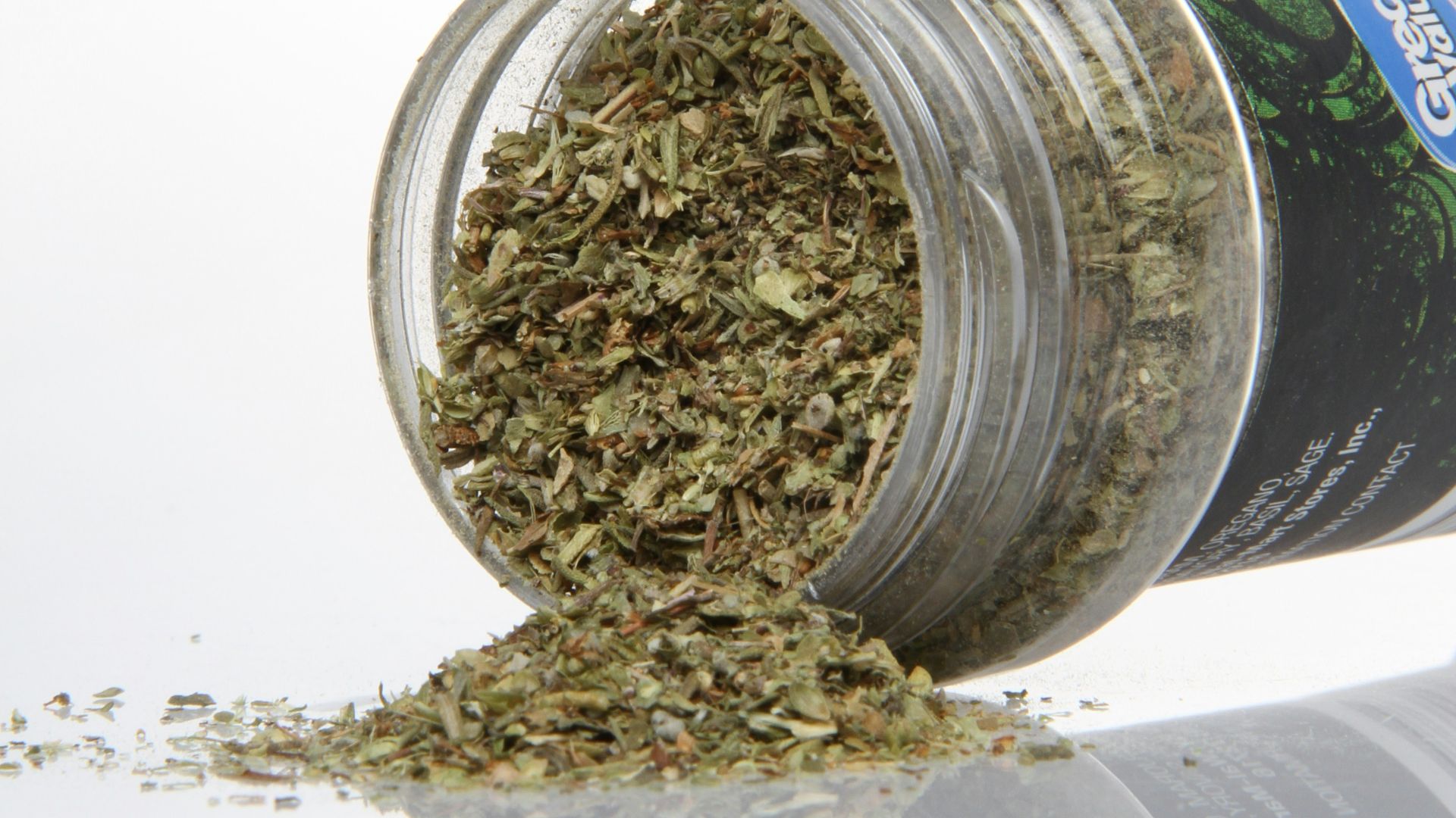 Dried herbs spilling from a clear container.