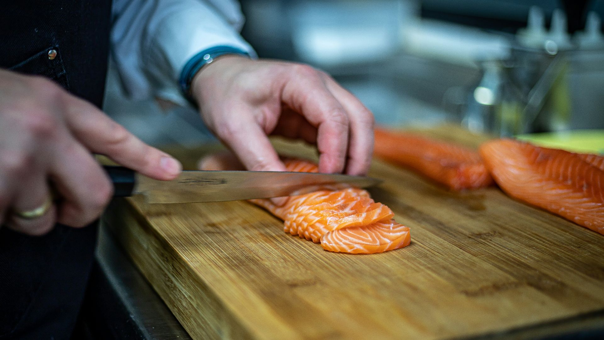 a person cutting up salmon on a cutting board