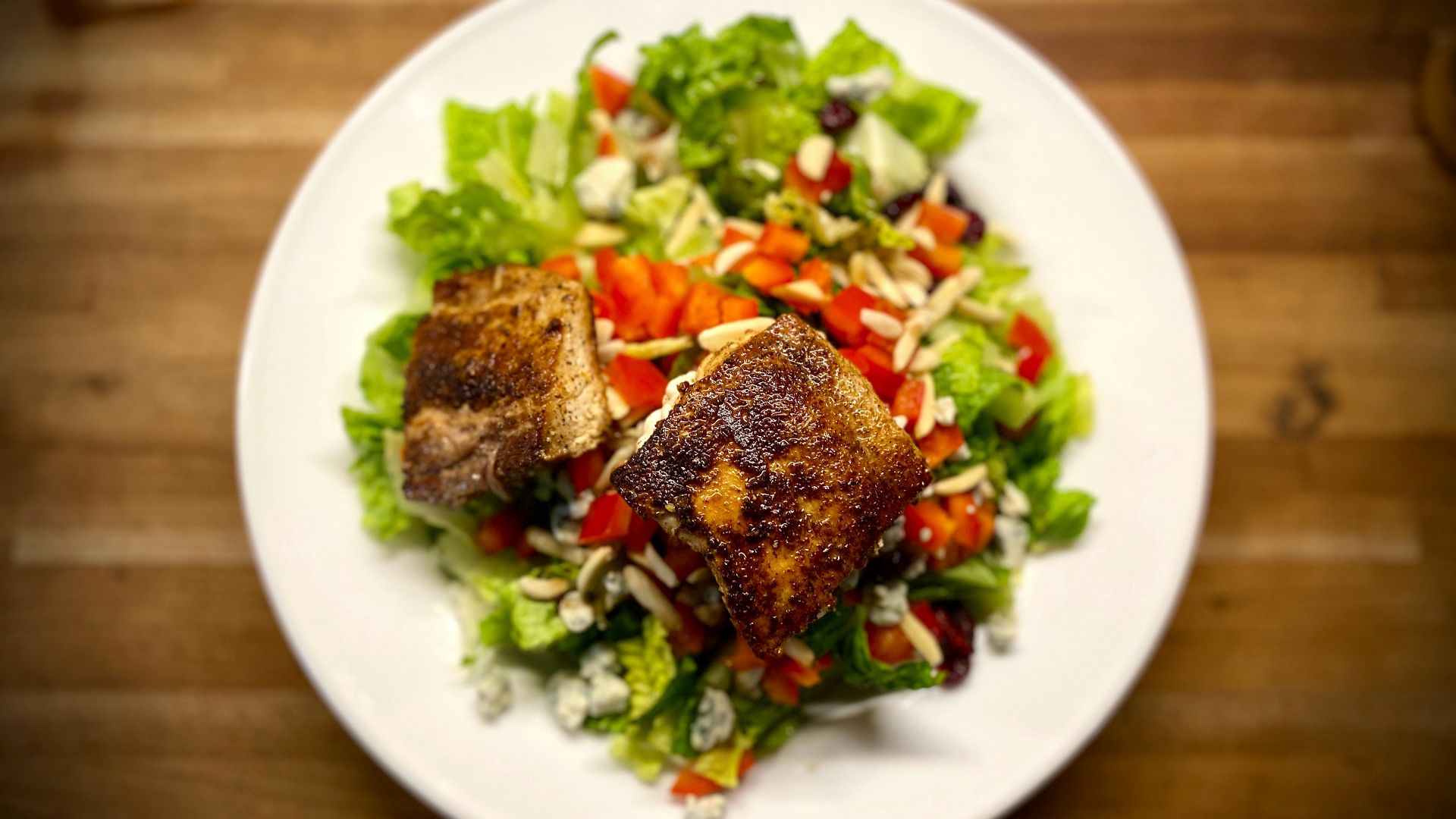 Grilled fish atop a fresh green salad