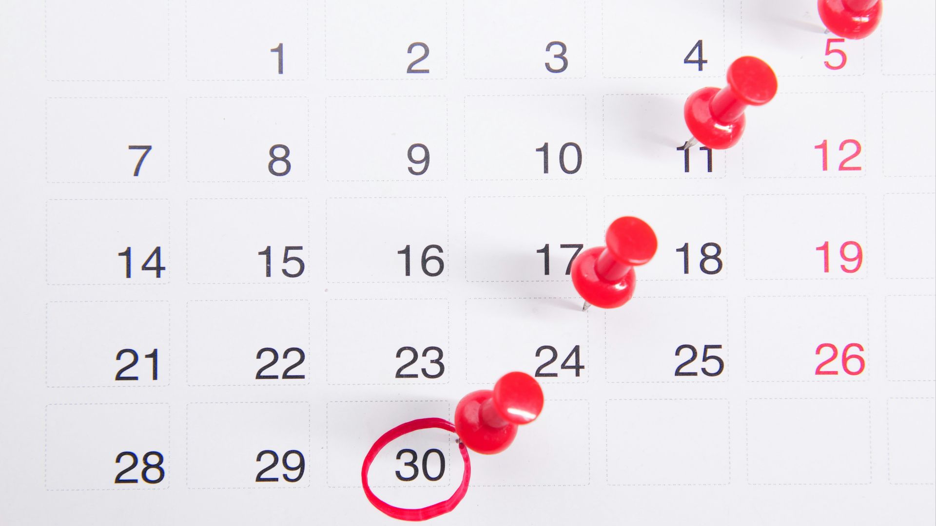 a calendar with red push buttons pinned to it