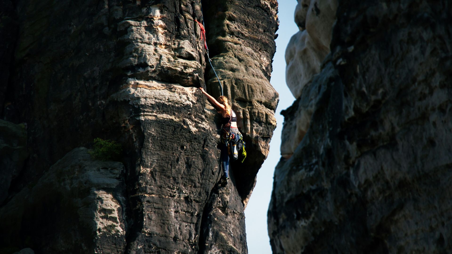 A rock climber ascends a steep cliff face.
