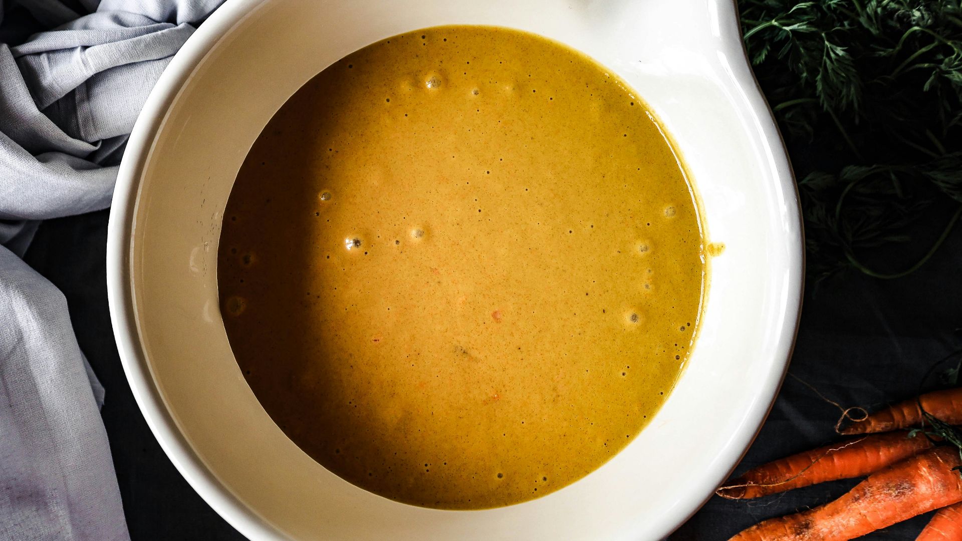 a bowl of soup with carrots and parsley