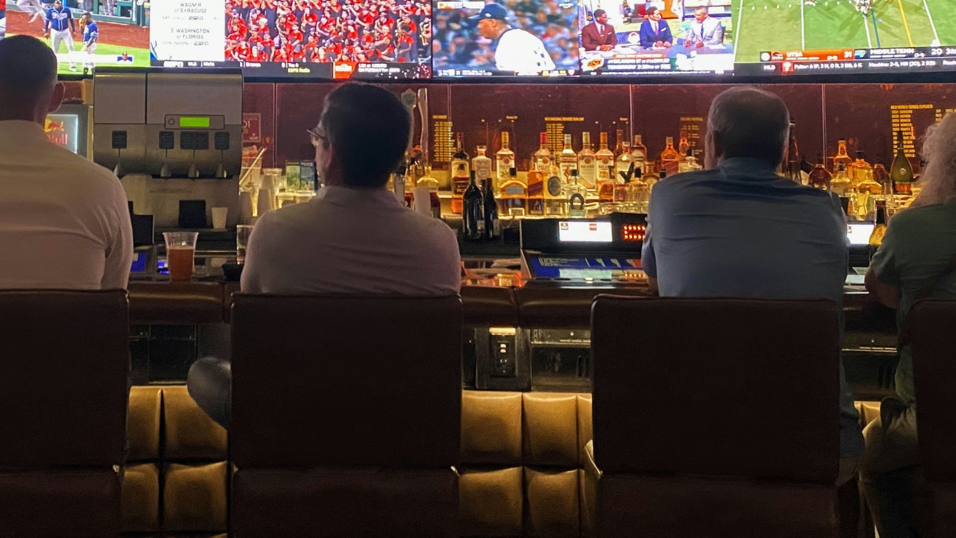 a group of people sitting at a bar watching tv
