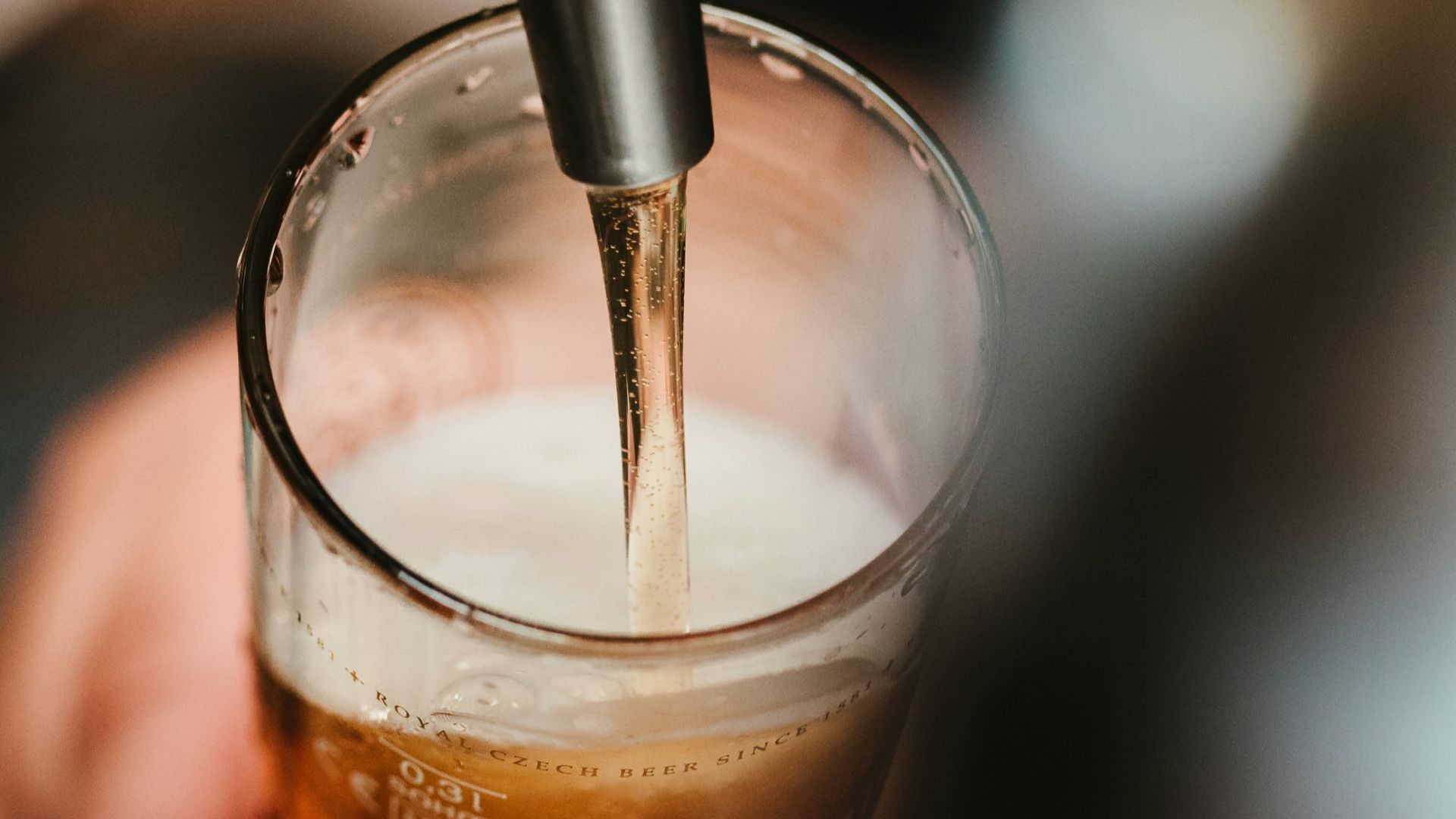 person filling clear glass with liquid