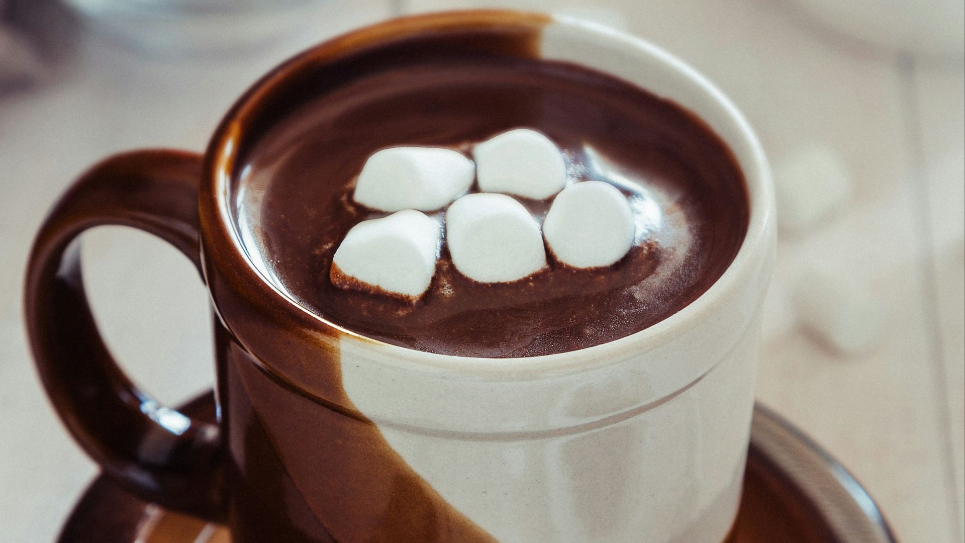 a cup of hot chocolate with marshmallows on a saucer