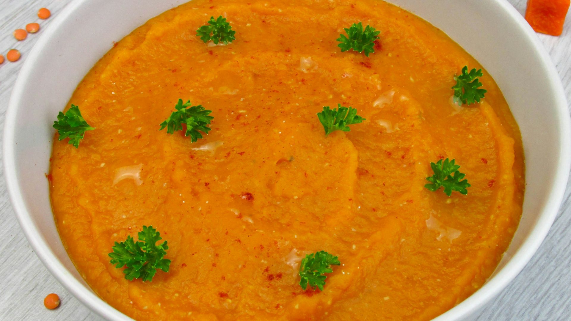 a bowl of carrot soup with parsley on top