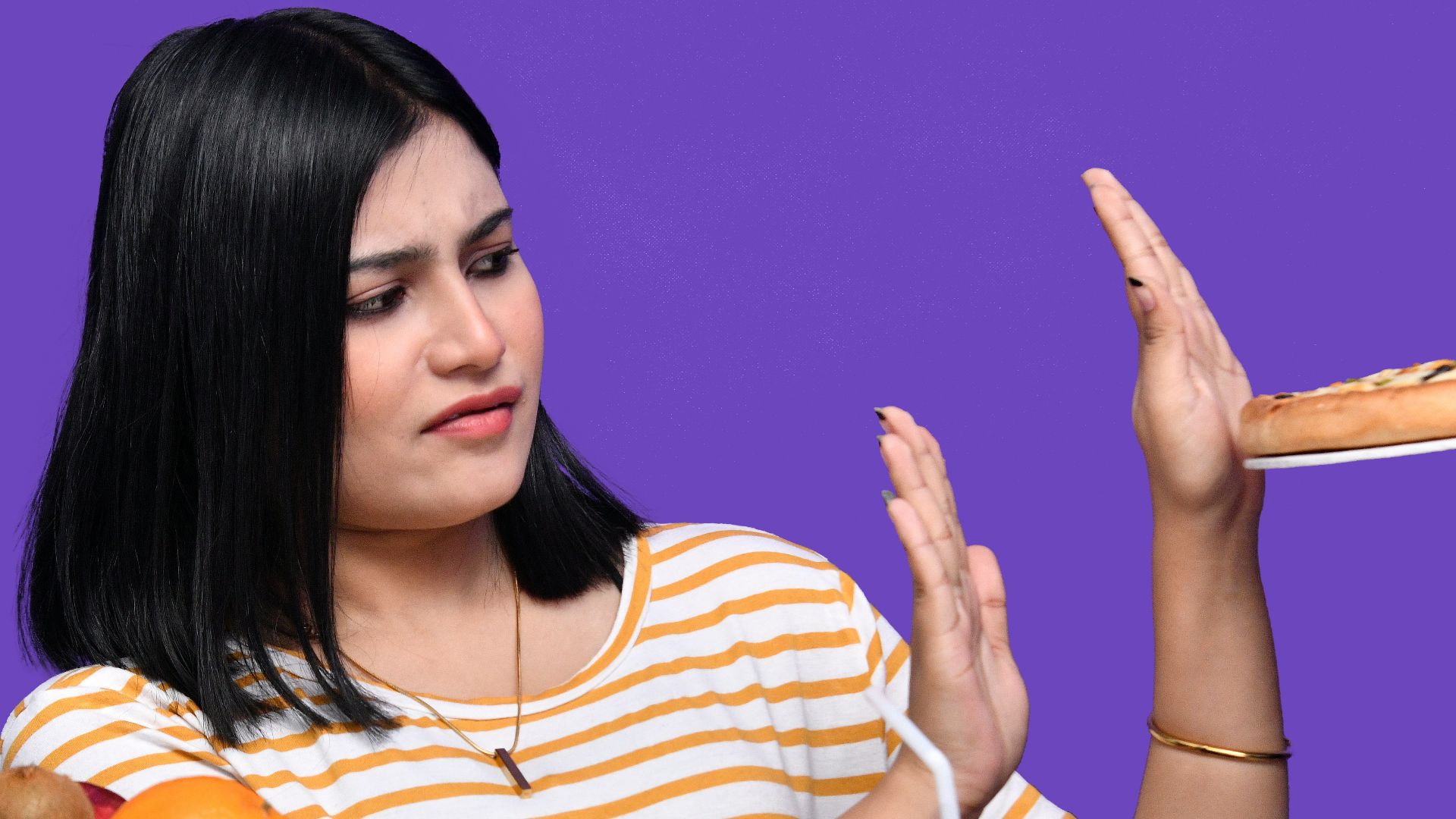 a woman sitting at a table with food and a bowl of fruit