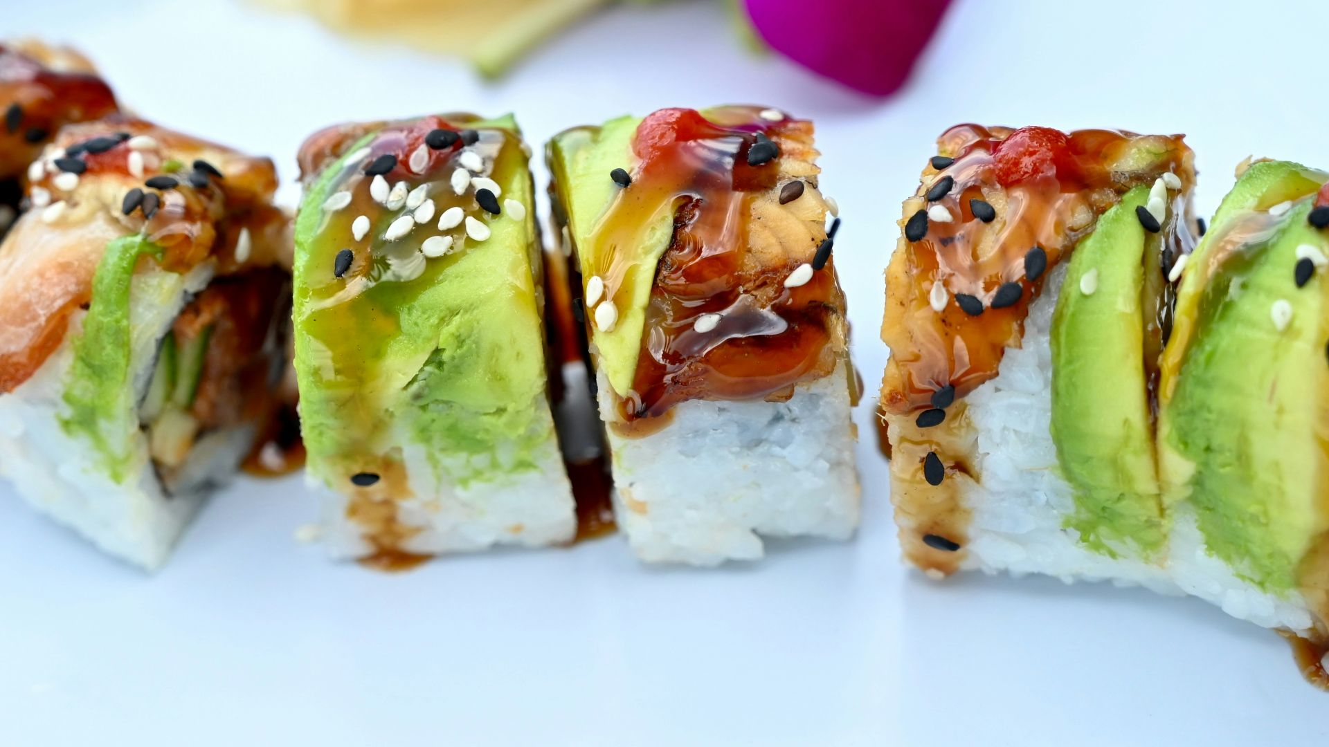A white plate topped with sushi next to a purple flower