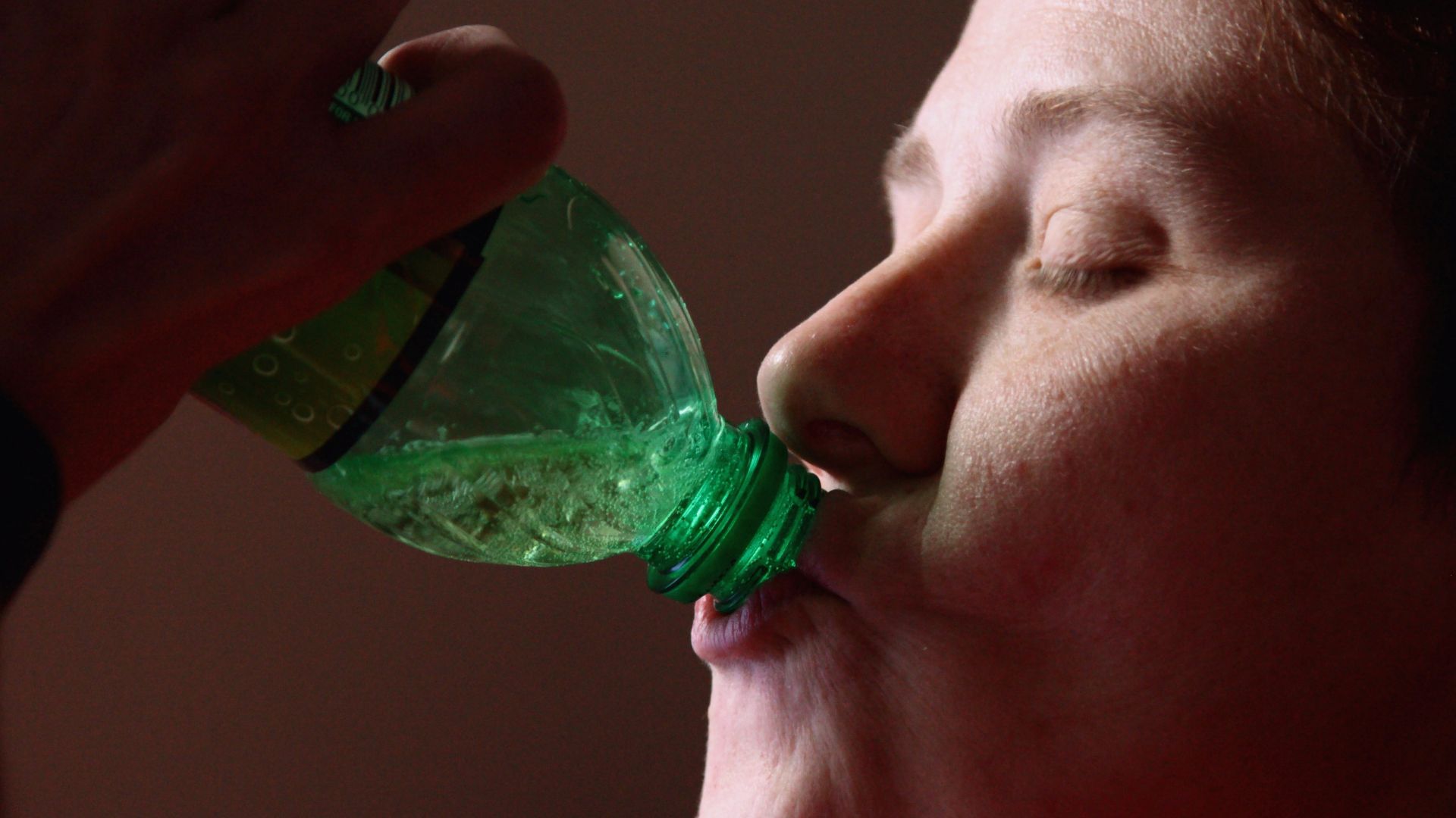woman drinking from green plastic bottle