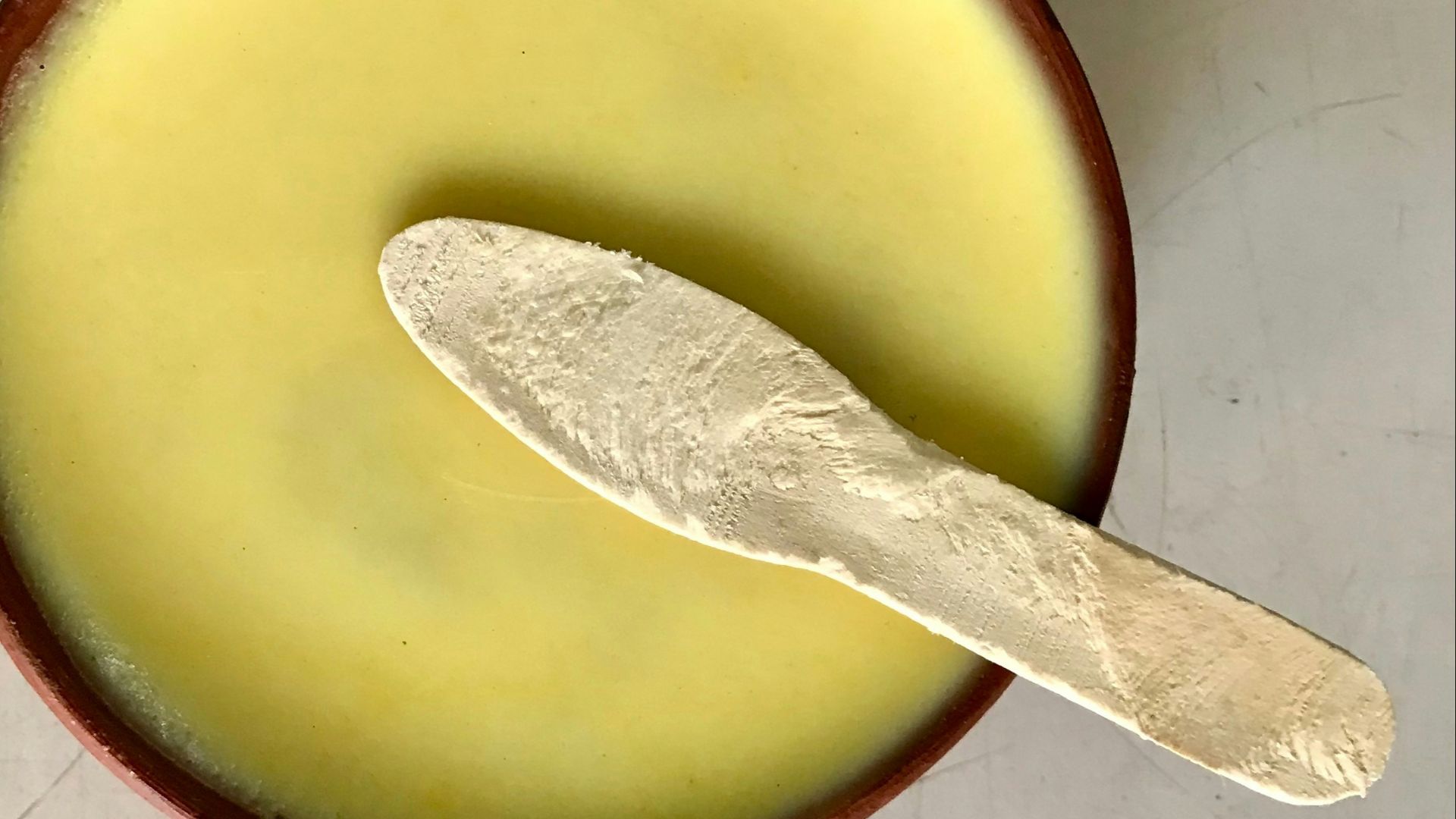 A spoon in a bowl with a liquid inside of it