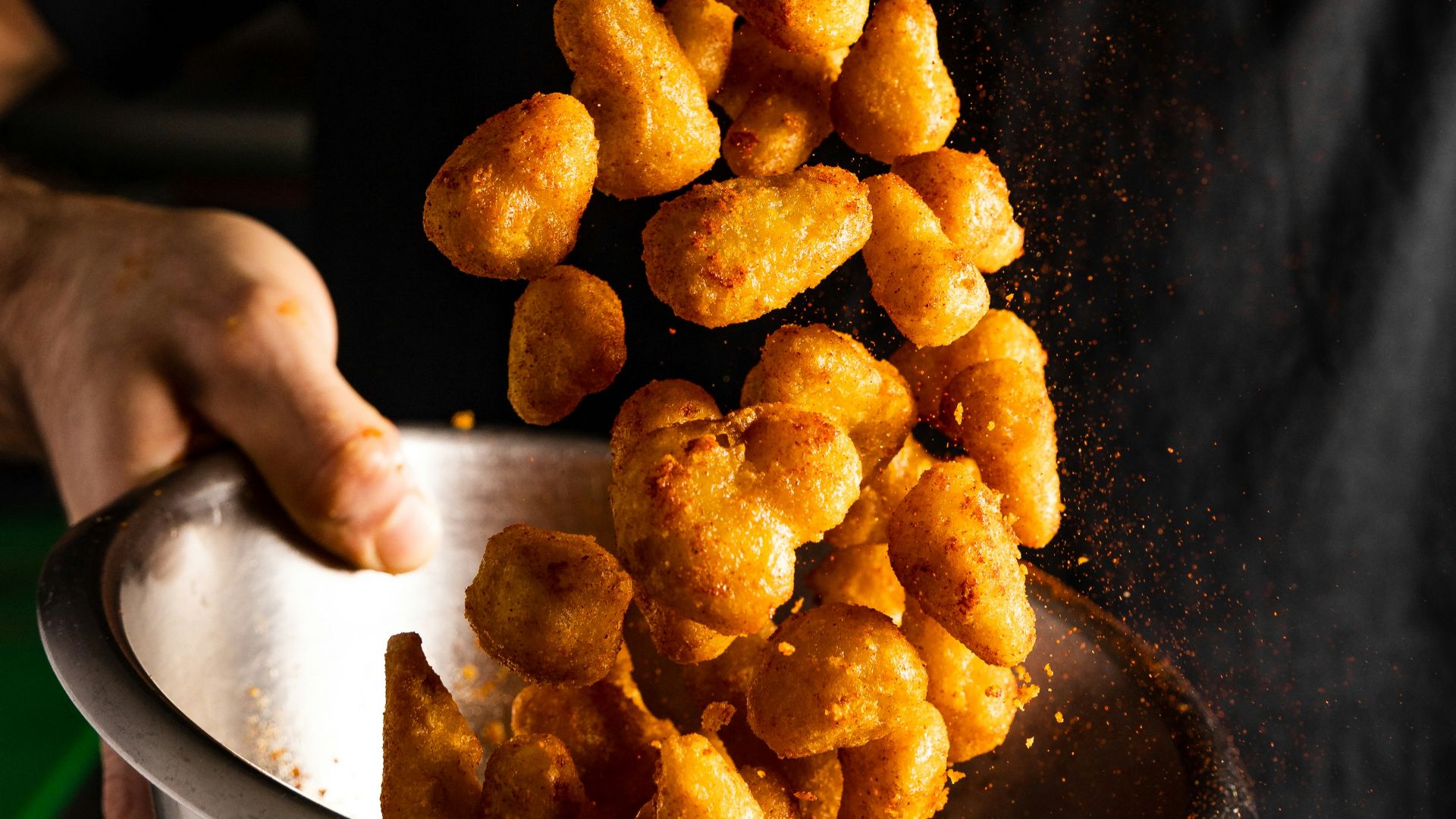 a person holding a bowl of fried food