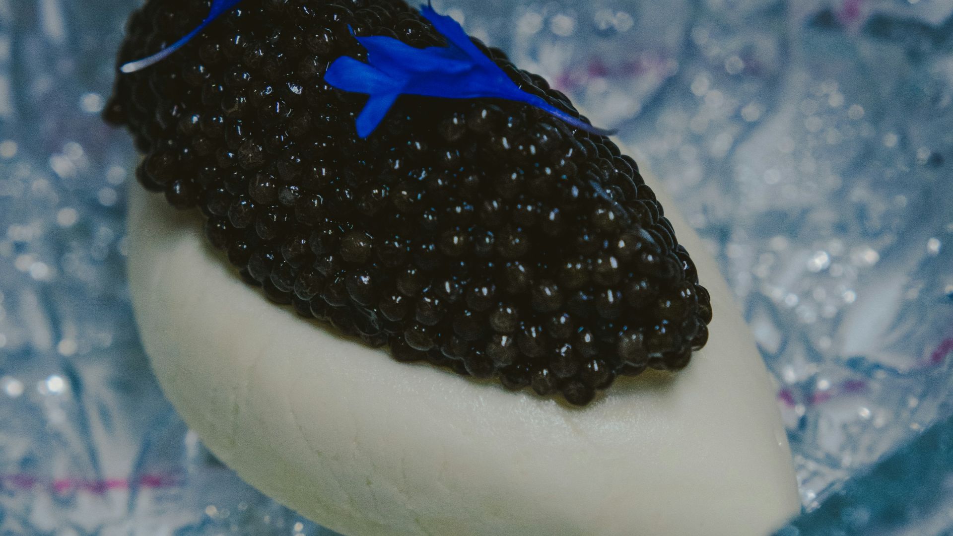 Caviar served on white cream in a glass dish.