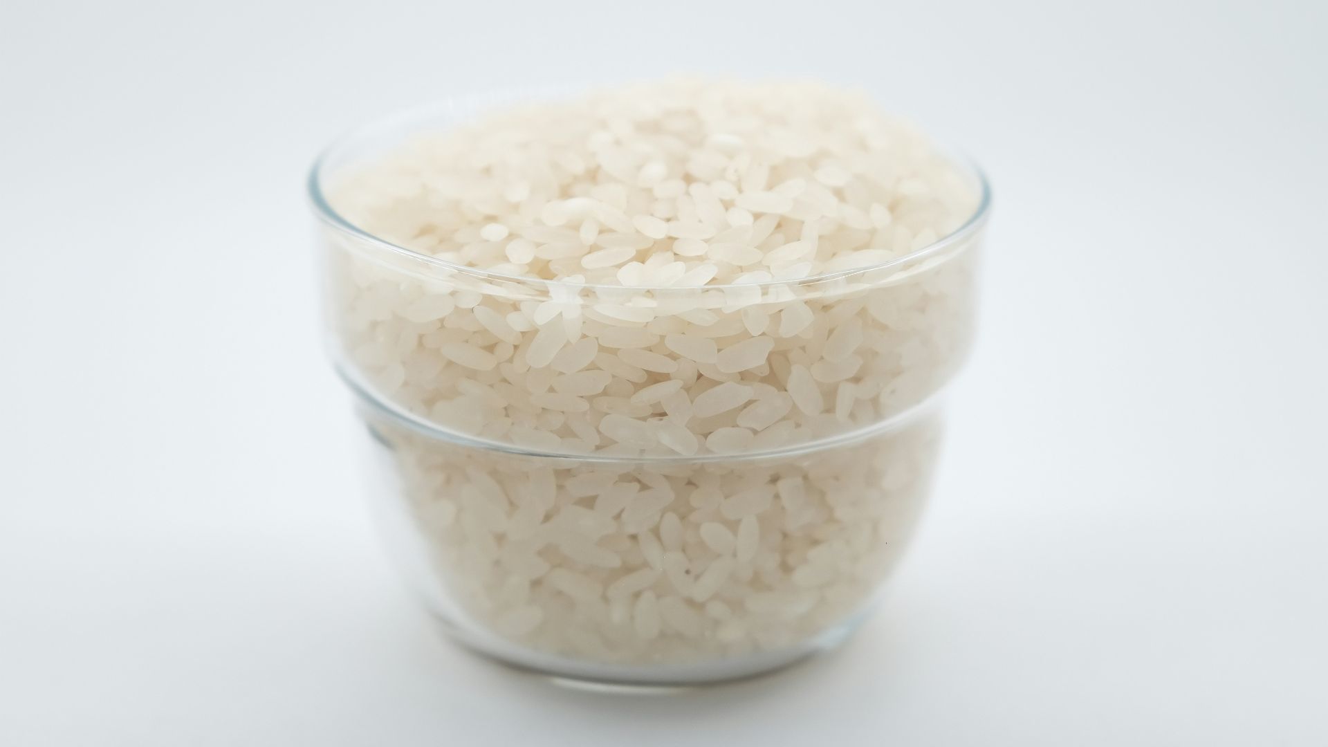 a glass bowl filled with rice on top of a white table