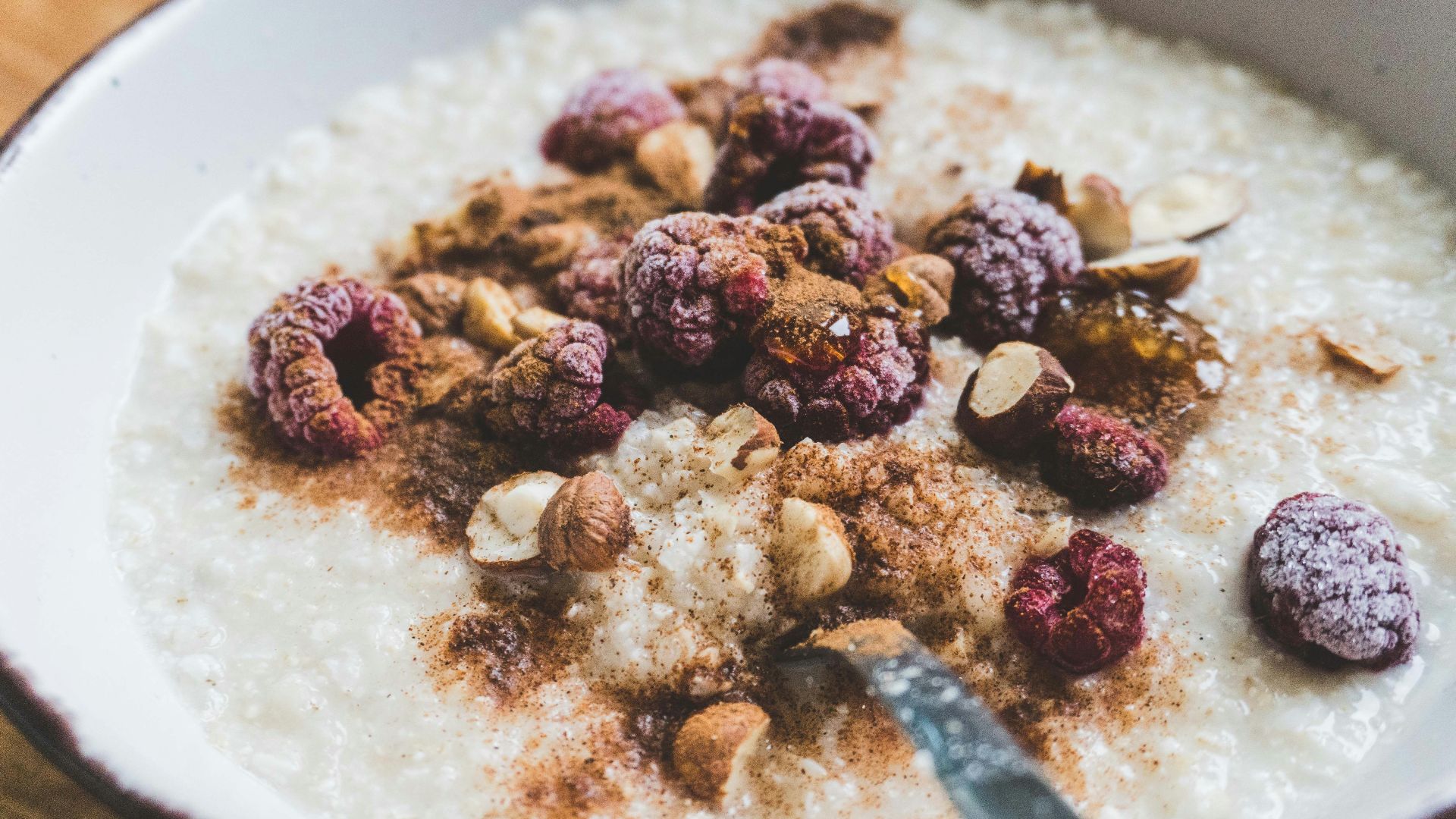 a bowl of oatmeal topped with nuts and raspberries