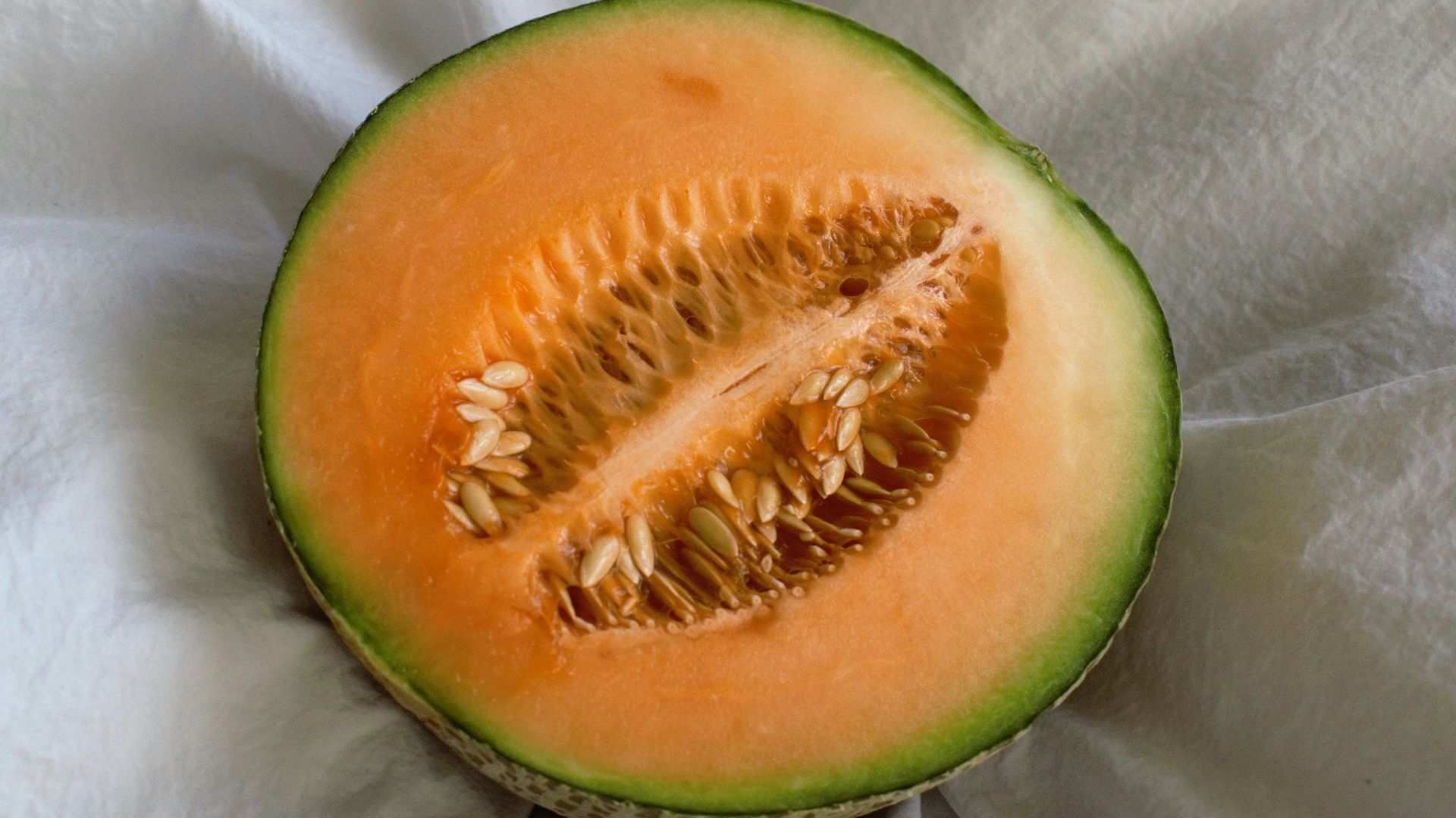 a cut in half melon sitting on top of a white cloth
