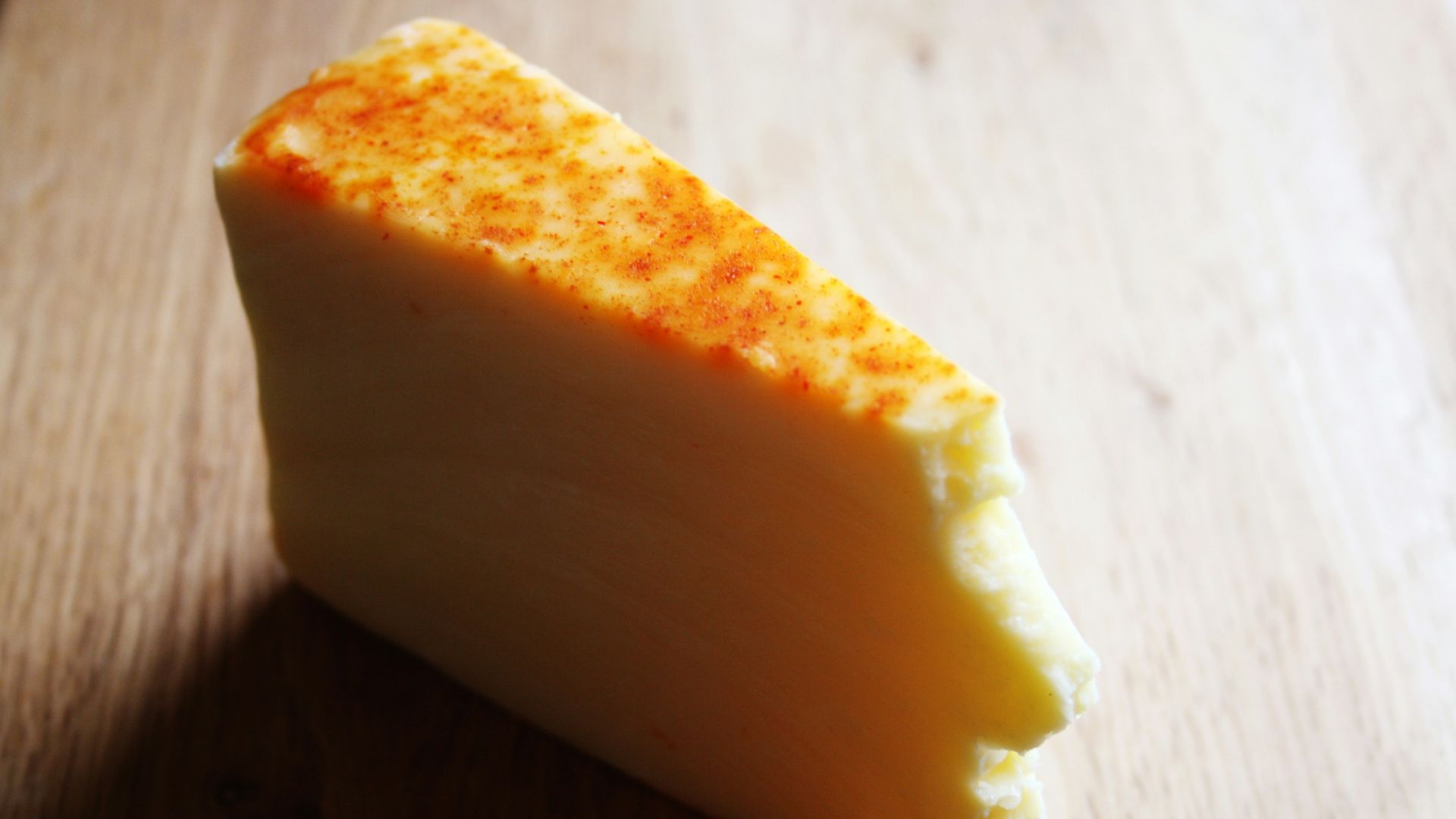A piece of cheese sitting on top of a wooden table