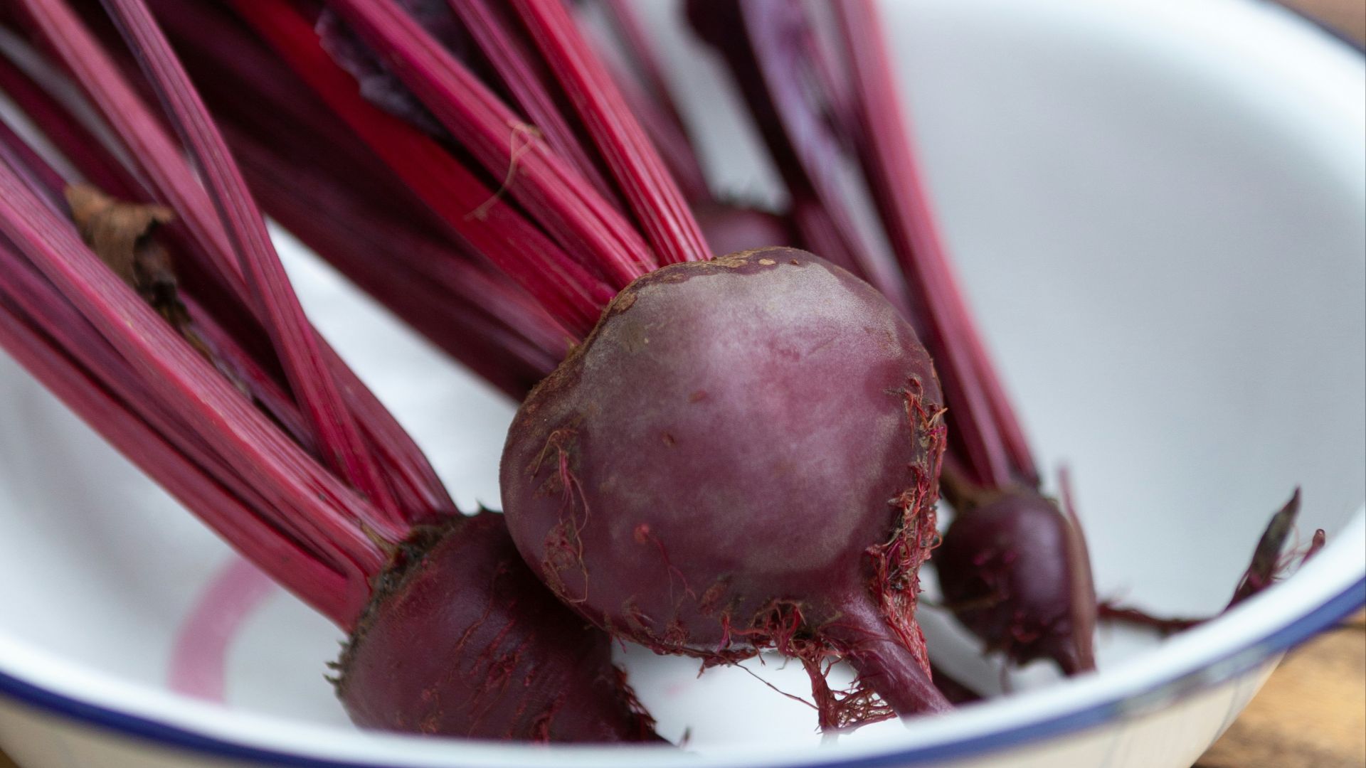 a bowl filled with beets sitting on top of a wooden table