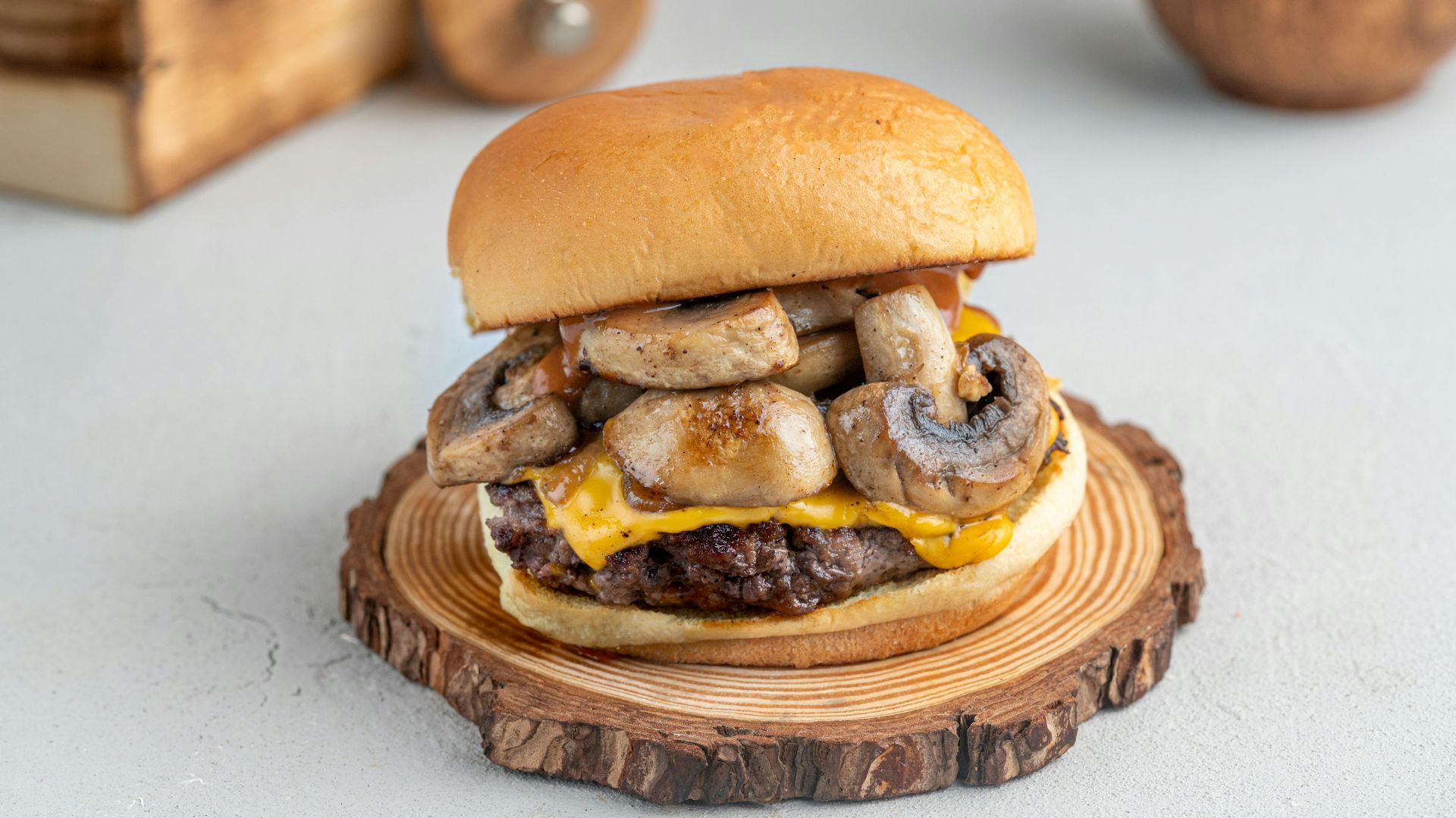 a cheeseburger with mushrooms on a wooden plate