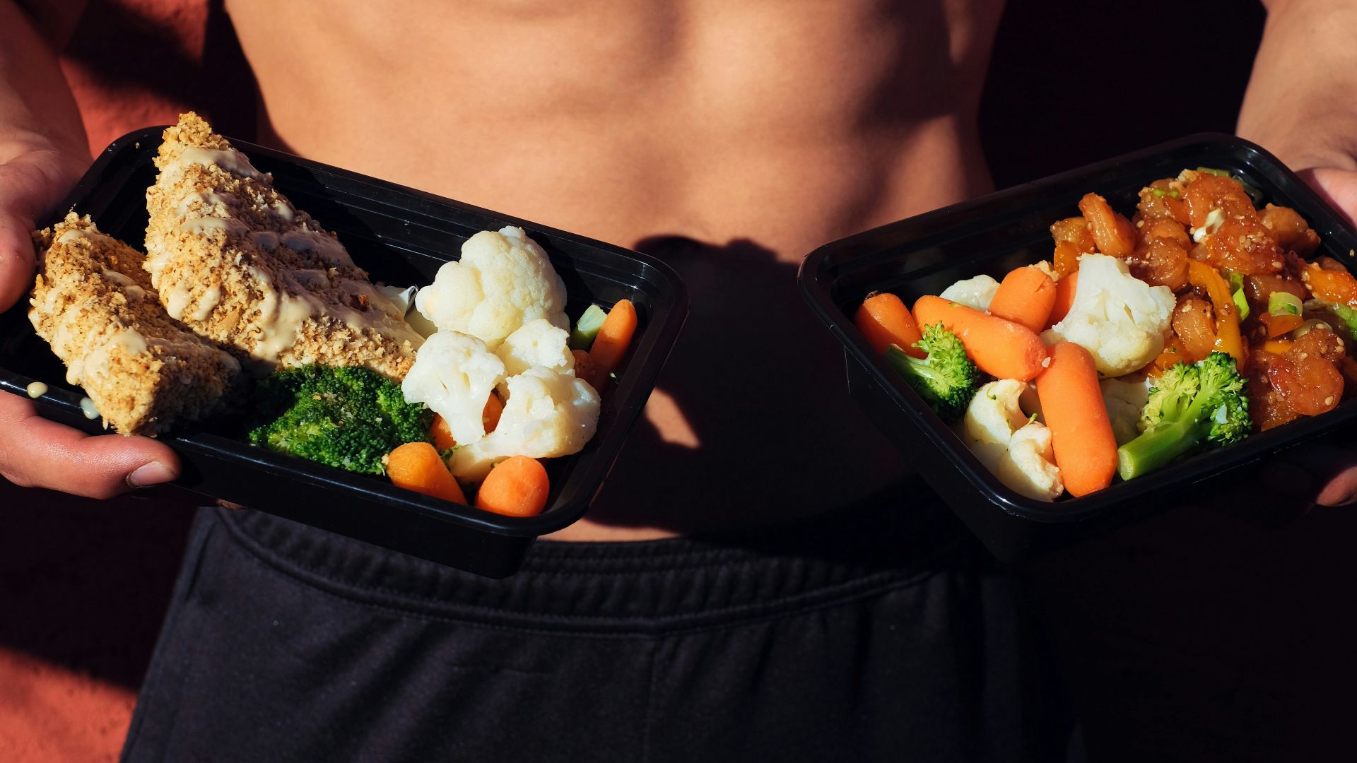topless man in black shorts holding cooked food