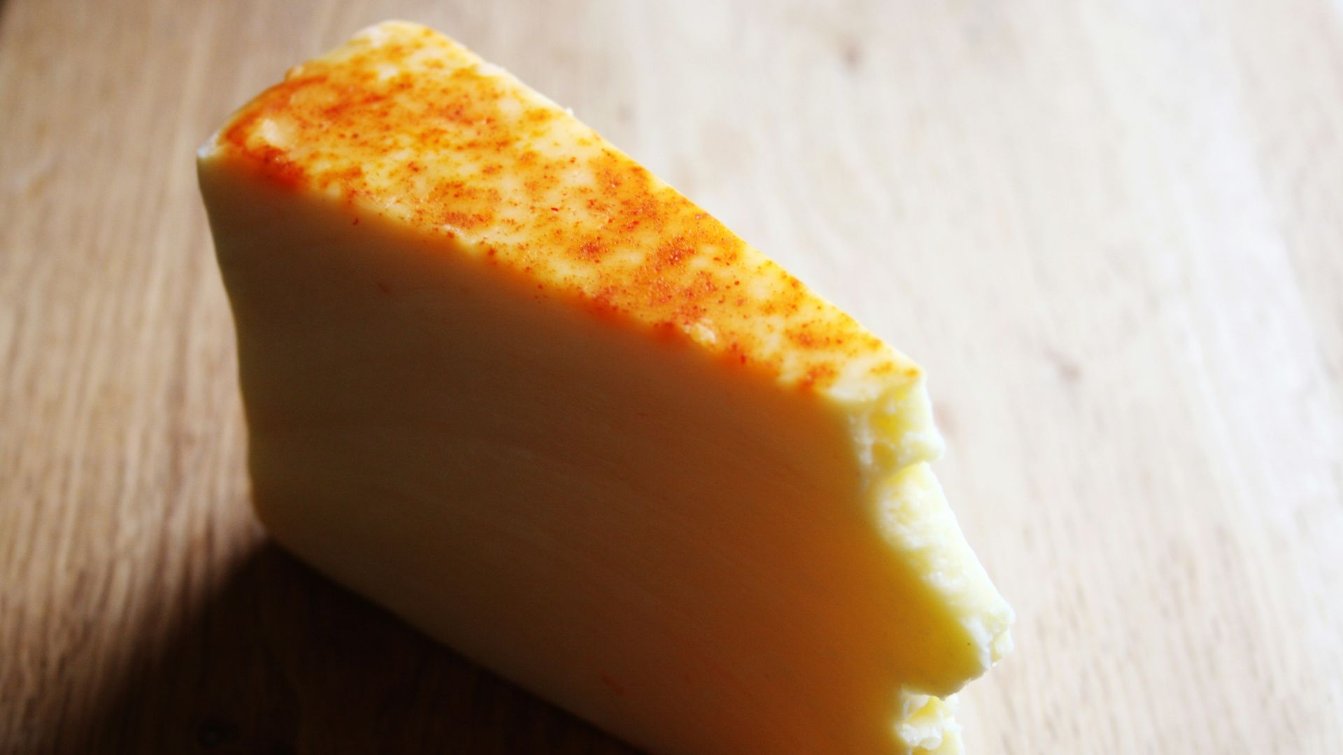 A piece of cheese sitting on top of a wooden table