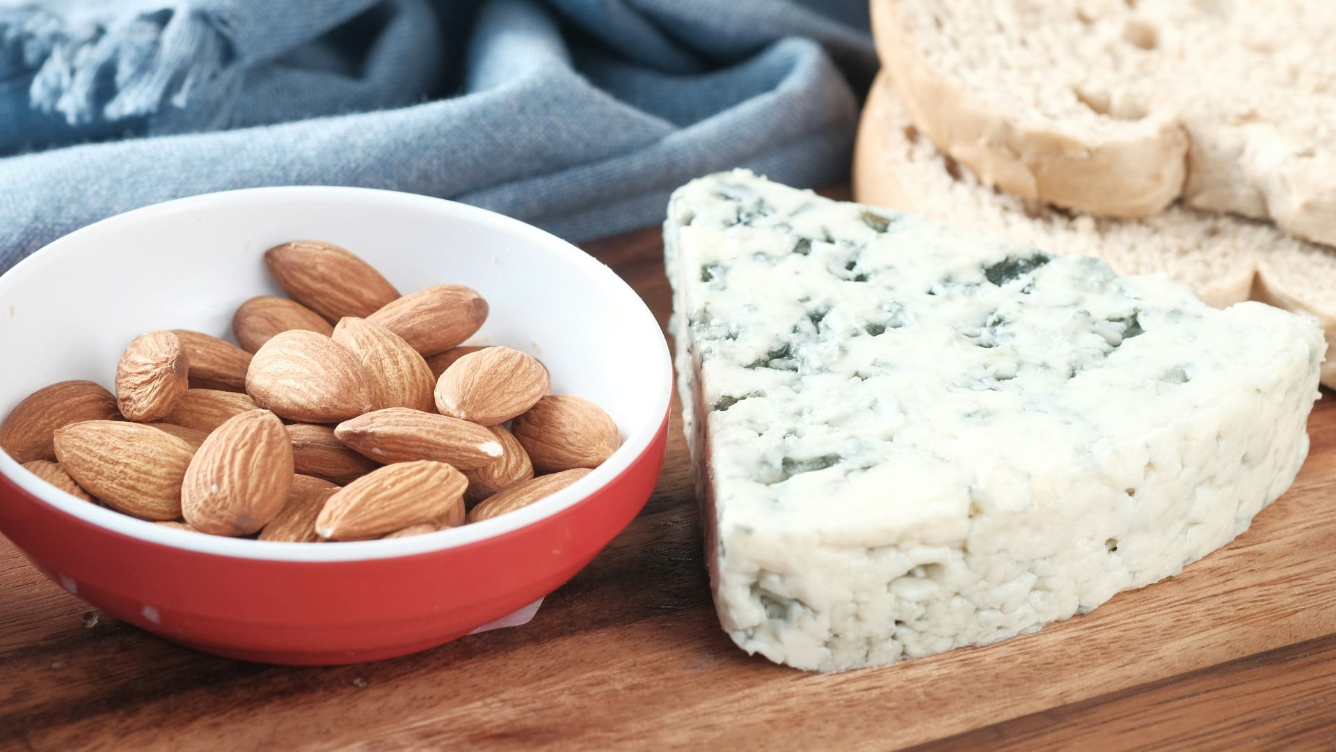 a bowl of almonds, bread, and an egg on a cutting board