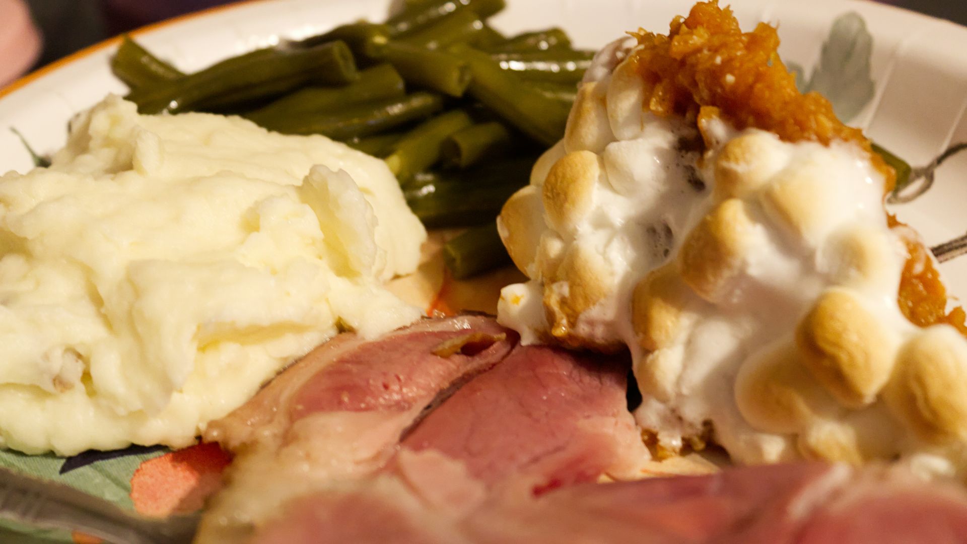 A white plate topped with meat, mashed potatoes and green beans