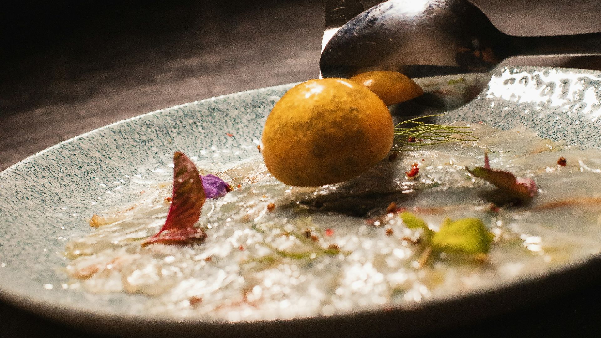person holding stainless steel spoon and fork eating on black table