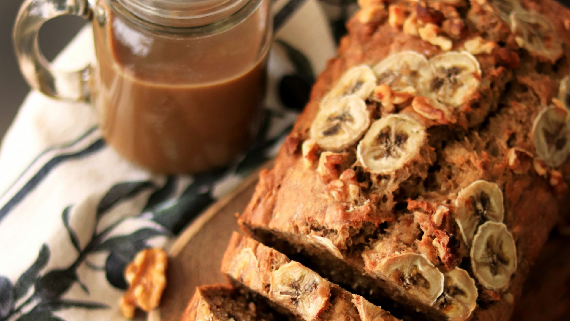 a loaf of banana nut bread sitting on top of a wooden cutting board