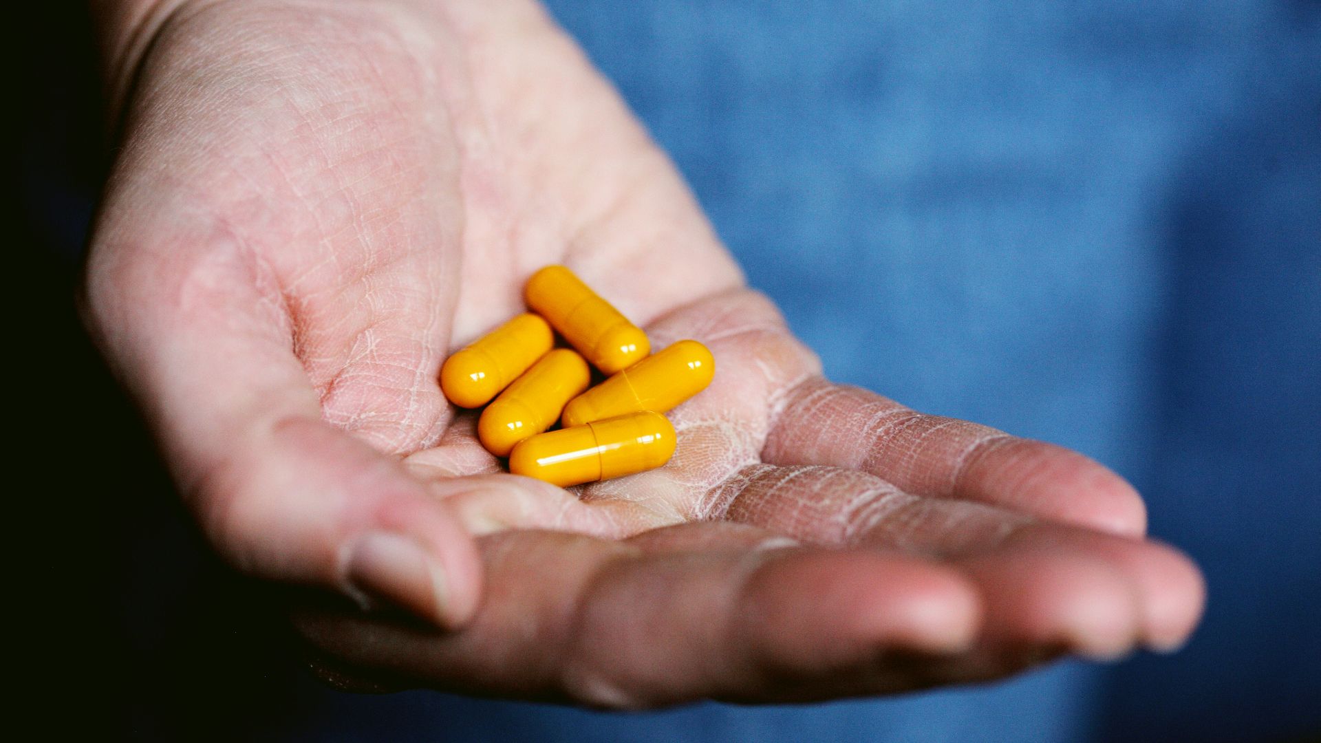 yellow medication pill on persons hand
