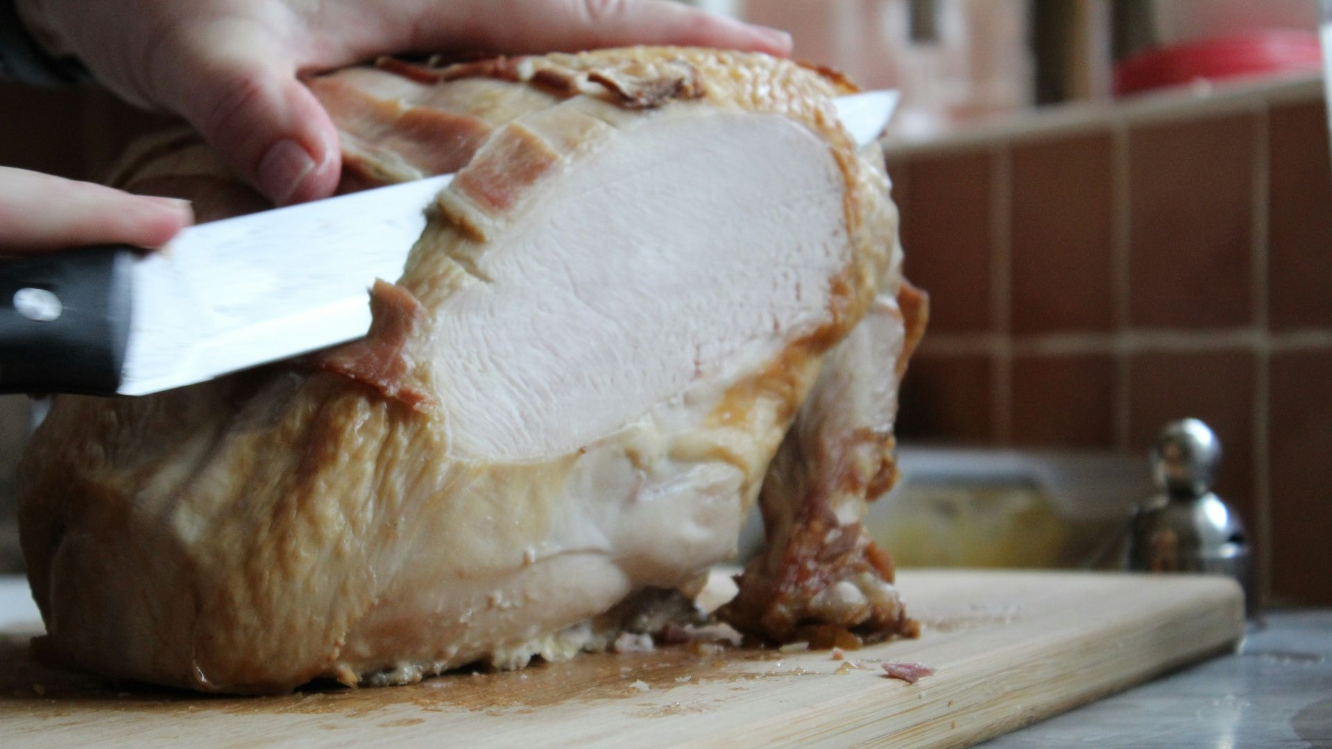 a person slicing a turkey on a cutting board