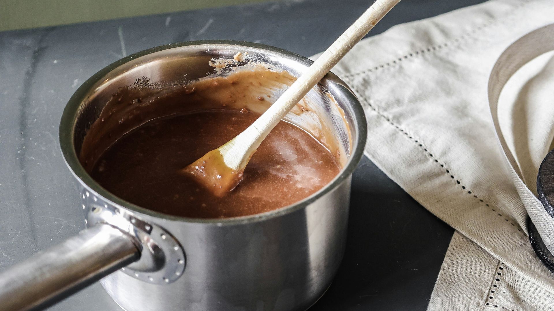 a pot of chocolate and a wooden spoon on a table