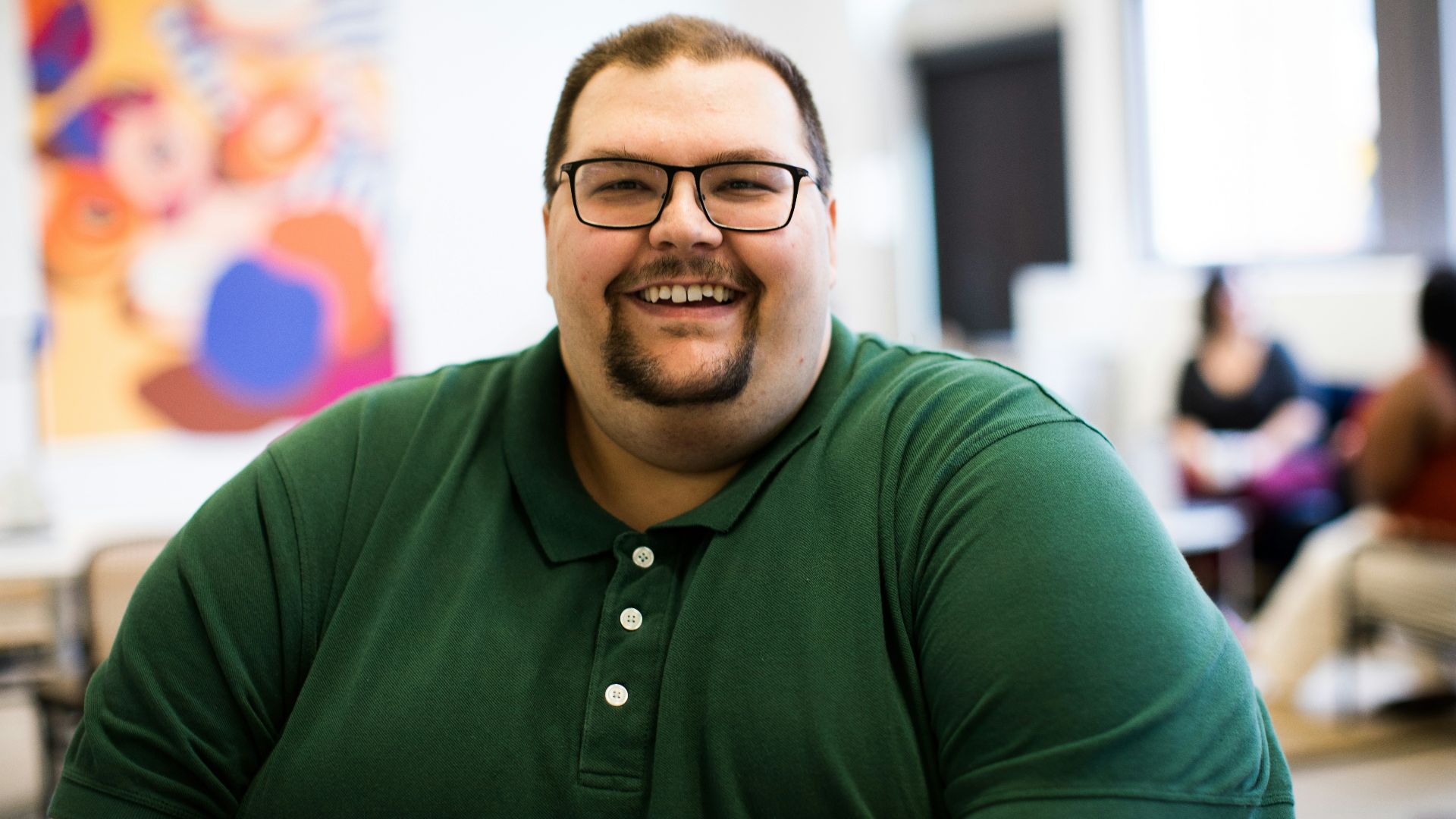 man sitting down wearing green polo shirt
