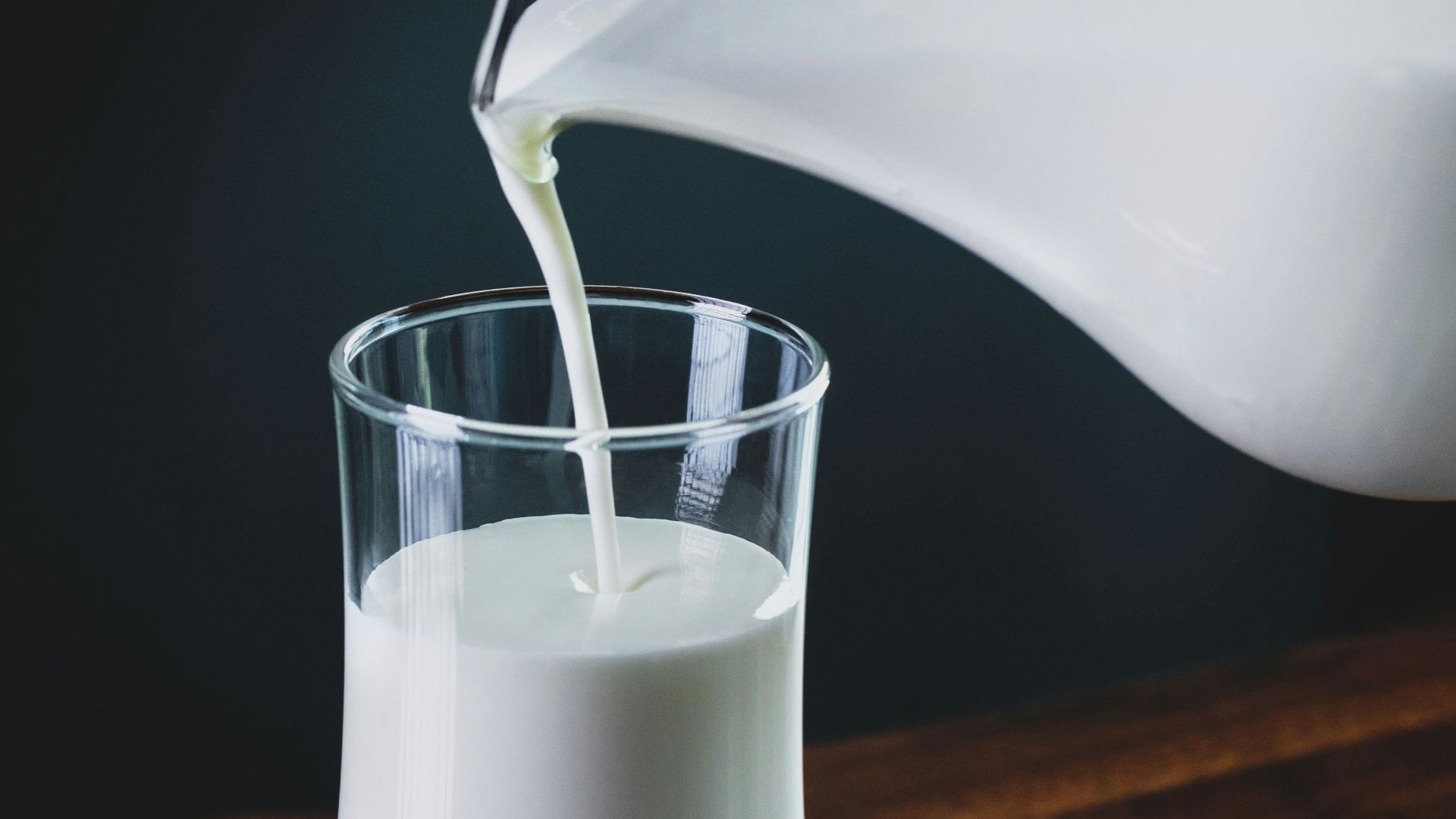 person pours milk into glass
