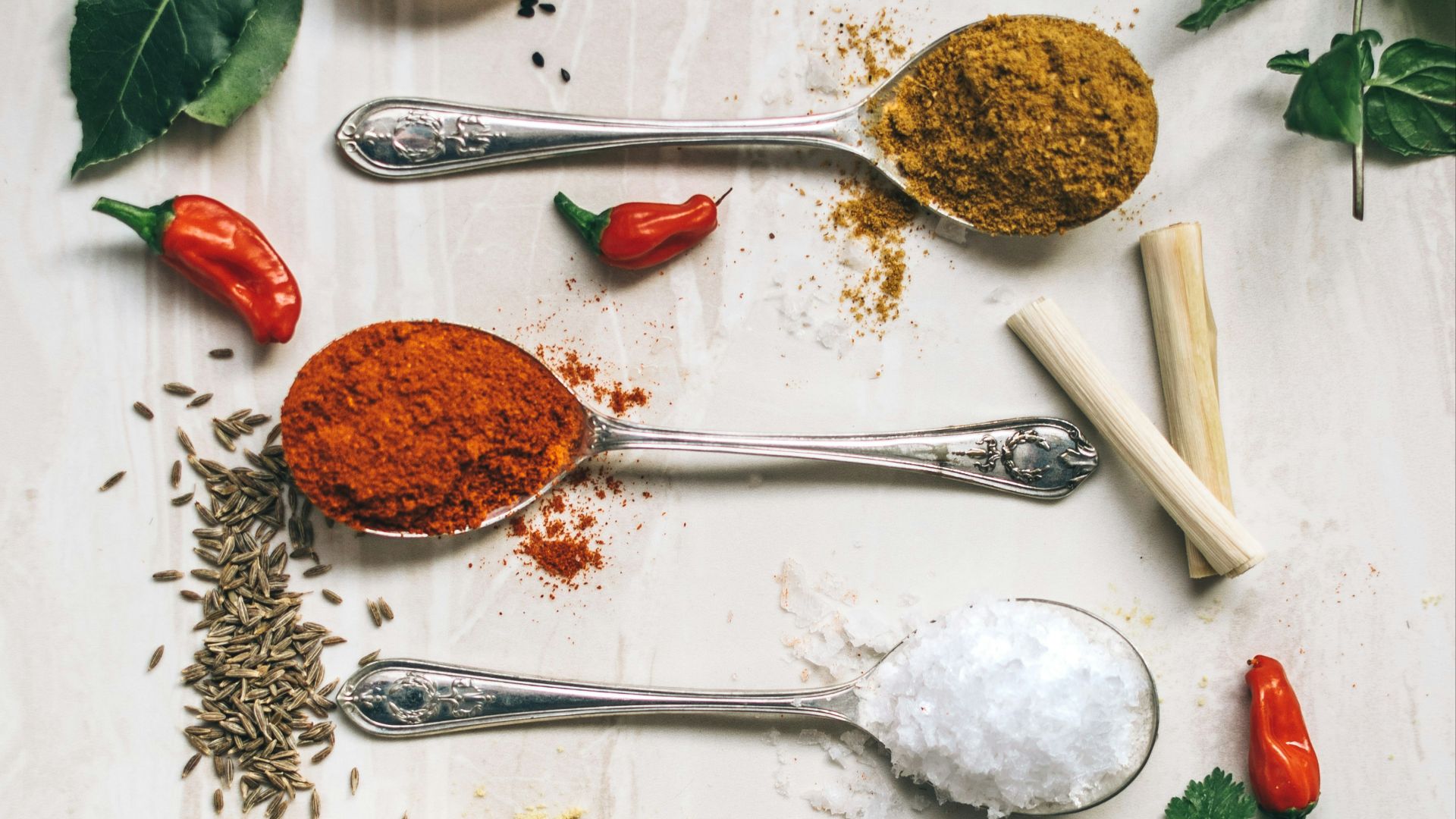 five gray spoons filled with assorted-color powders near chilli
