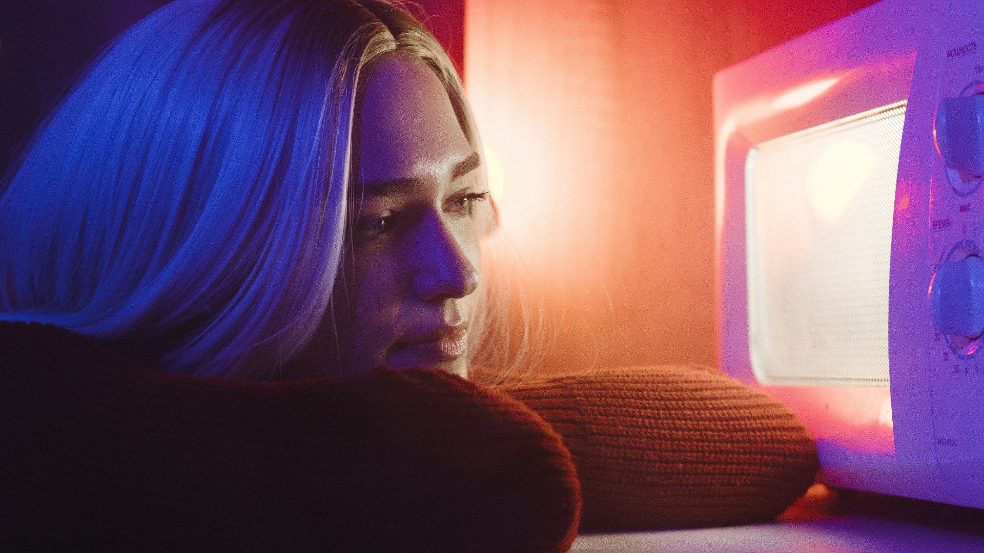 woman in black long sleeve shirt sitting beside white microwave oven