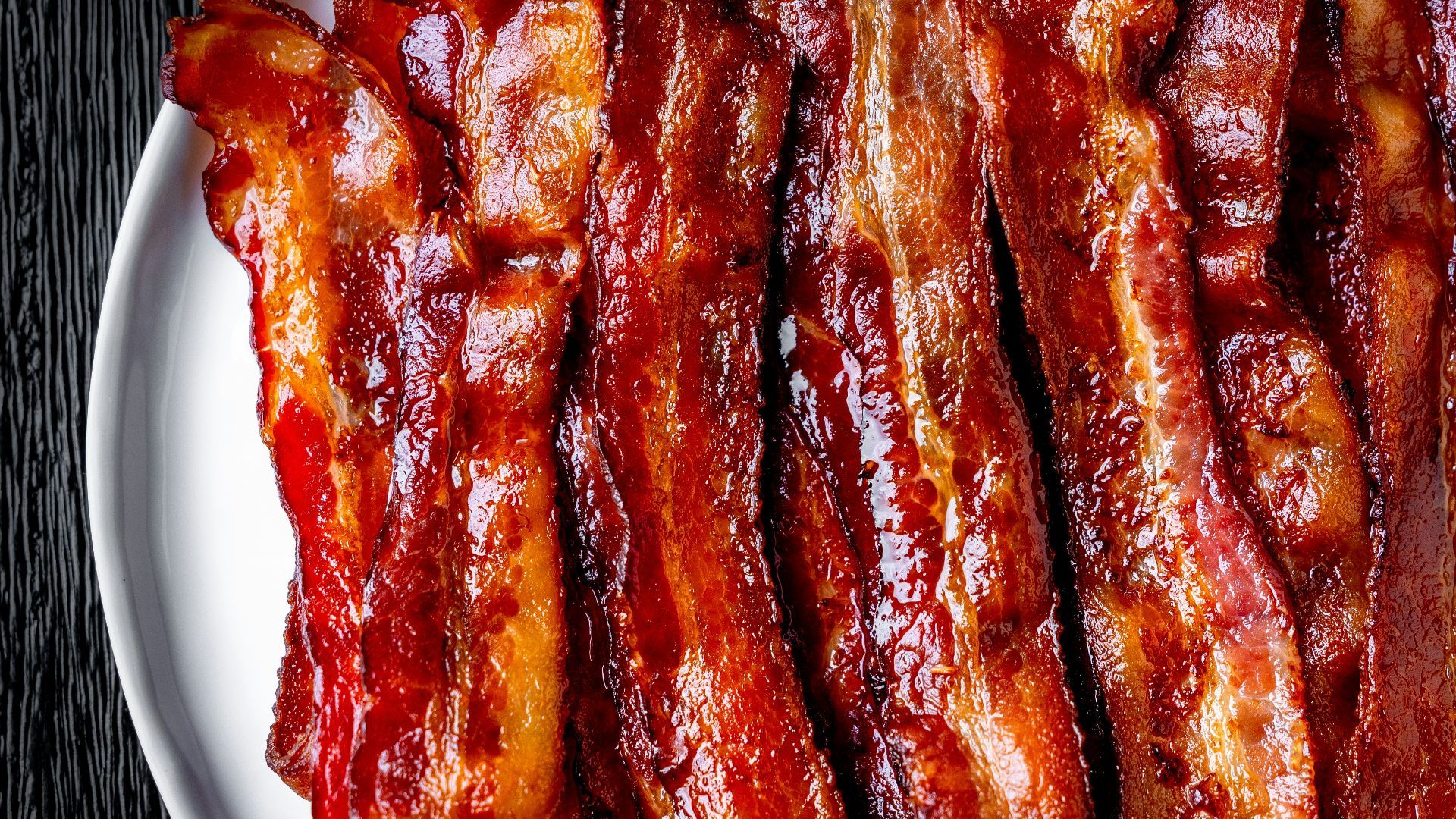 a white plate topped with bacon strips on top of a table