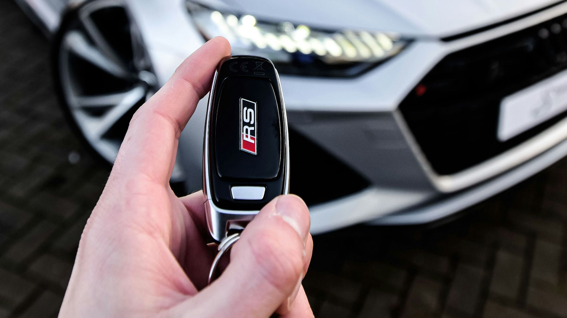 a person holding a car key in front of a silver car